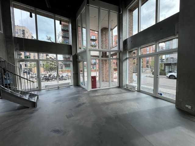 I det åbne, rummelige lokale ser vi lyse vinduer og store glasdøre. Der er en bred trappe og et rødt affaldskur, som er