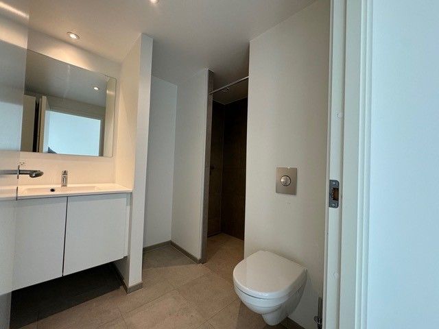 En moderne badeværelse med hvid tøjvask, spejl, hvid toilet og håndvask med vandhane