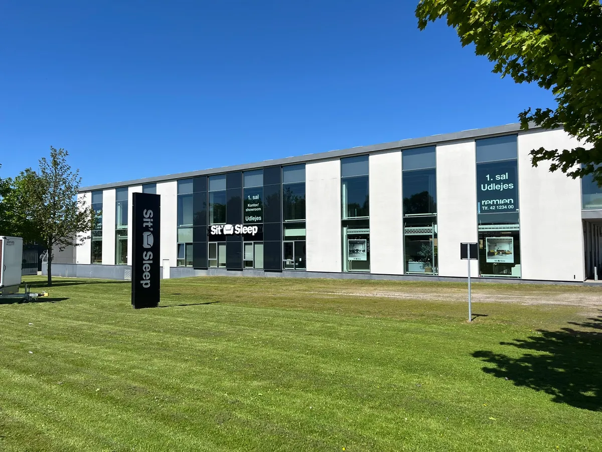 Store, hvide bygninger med glasruder og møbelforretning Sit og Sleep. Alle bygninger har reklameskilt og smukke