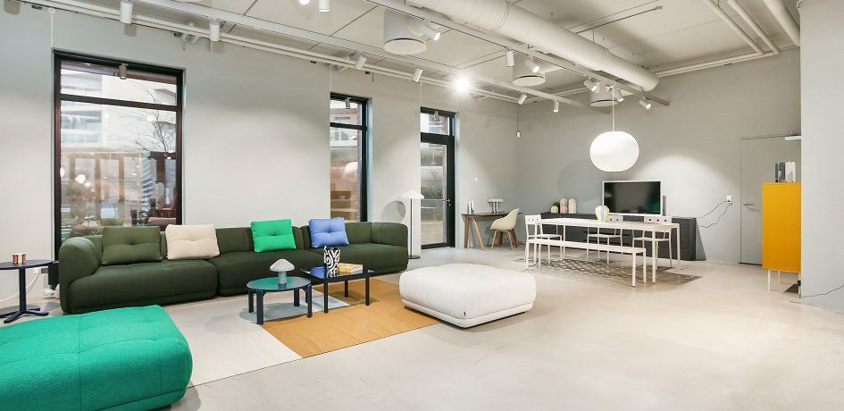 Moderne stue med lyse, komfortable møbler og en stor sofa, der er udsmykket med farverige puder og en stor, hvid kuglelampe