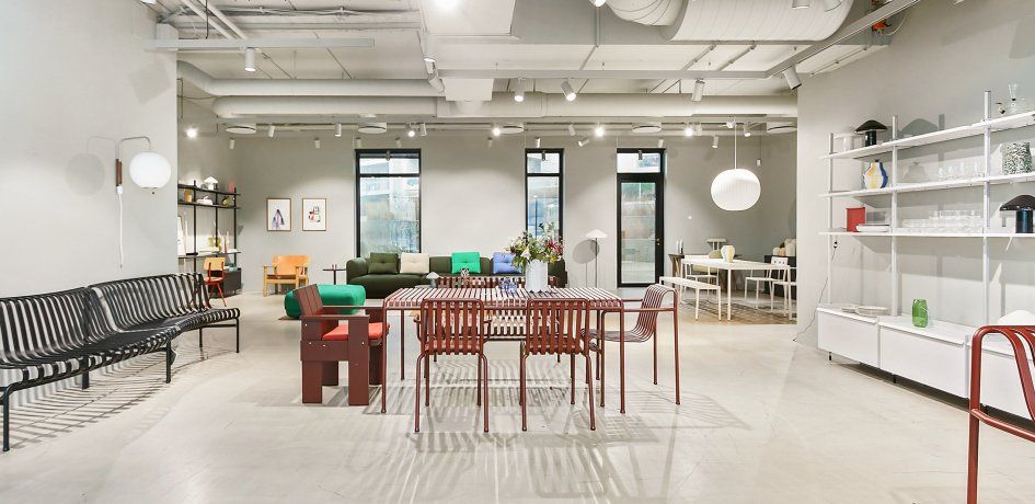 Moderne interiør med hvide vægge, loftsvinduer og høje lofter, hvor der er placeret møbler som sofaer, stole, skriveborde og