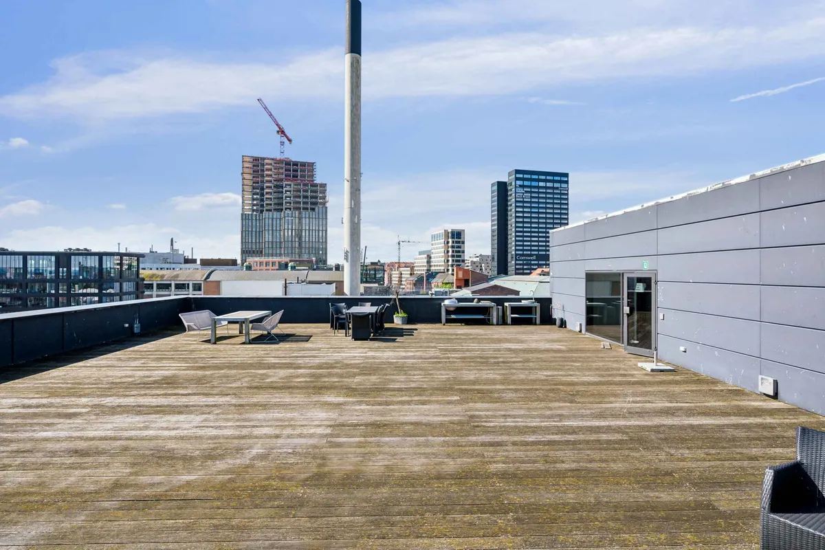 Moderne kontor med udsigt over Aarhus bymidte, terrasse med møbler, og i baggrunden bygninger og et tårn under opførelse