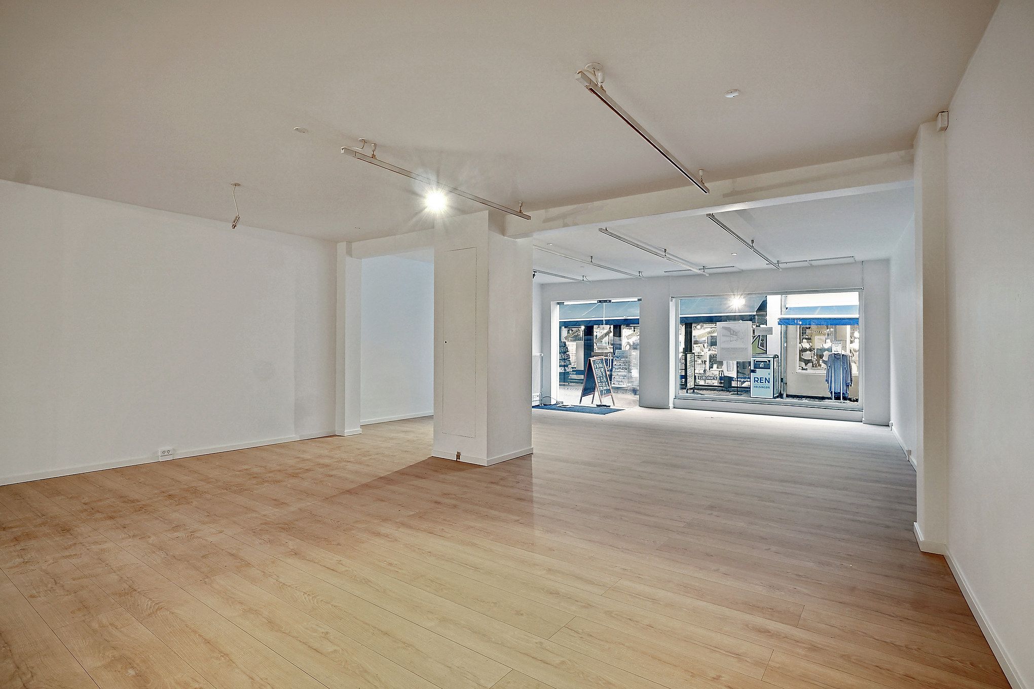 Stort lyst lejemål med store vinduer og lyse loftsbelysninger i nyt og velplejet stand. Store lyse gulve og hvide vægge.