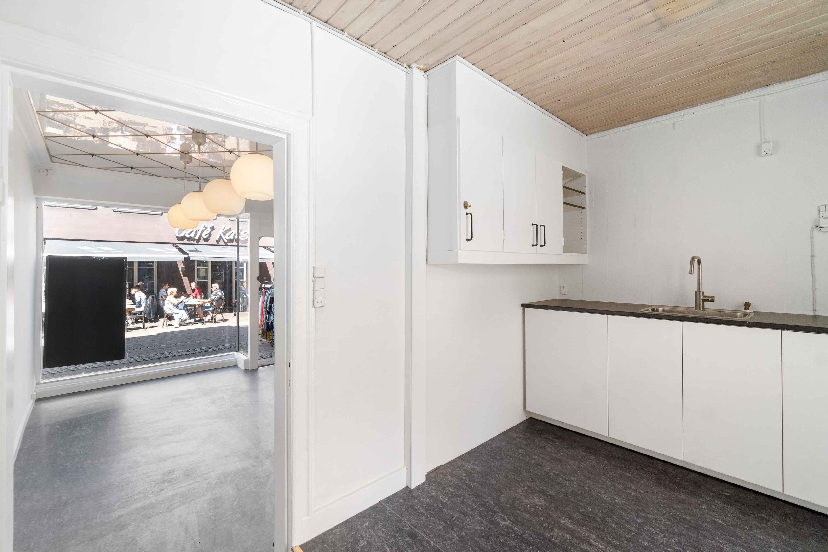 Lejemålet tilbyder en nybutik med moderne køkken og lyse loftsvinduer. Køkkenet har hvide skabe og en rustfri stål vandhane.