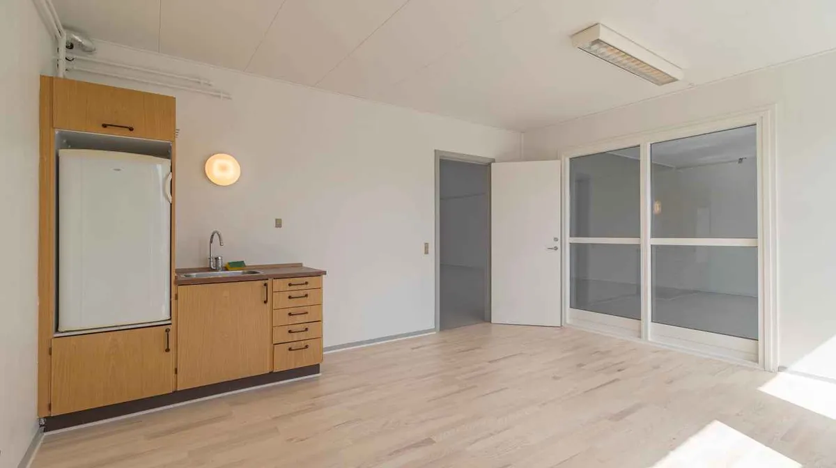 Lejlighed med moderne køkken og en stor køleskab samt en åben dør, der giver udsigt til et glasparti og udendørsområdet