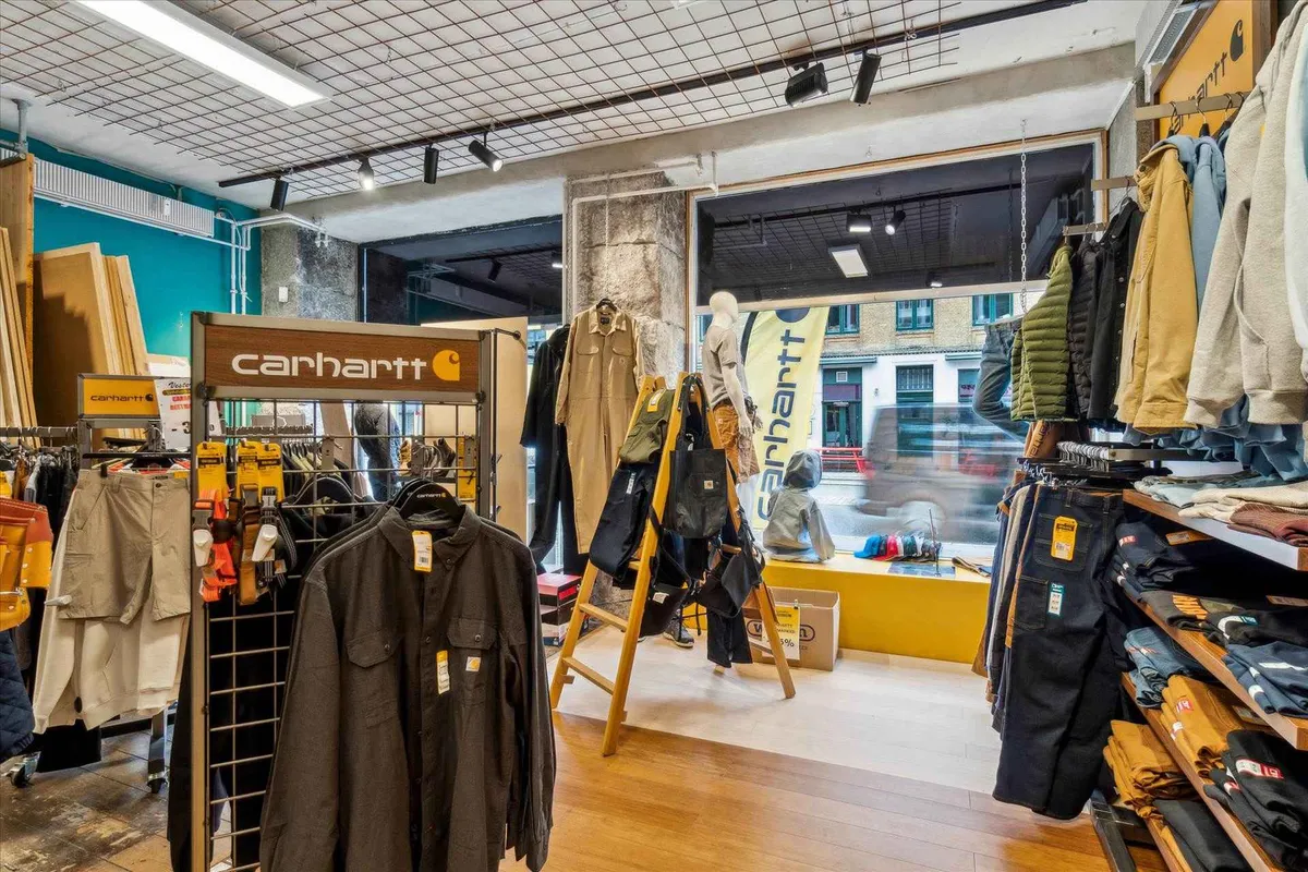 Carhartt butik med tøj på stativer og hylder, gulv med brædder og maneken med tøj i vinduet