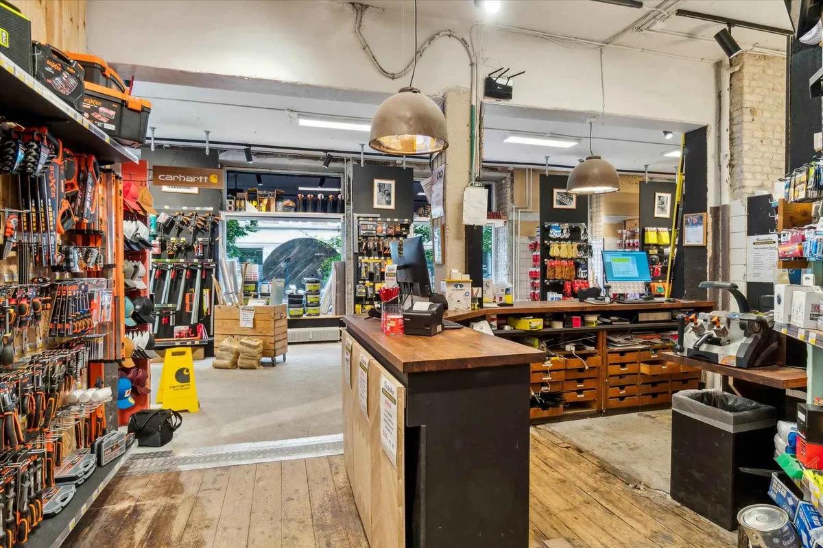 En møbelforretning med værktøj, slibemaskiner og arbejdsudstyr udsat på hylderne og bag skranken