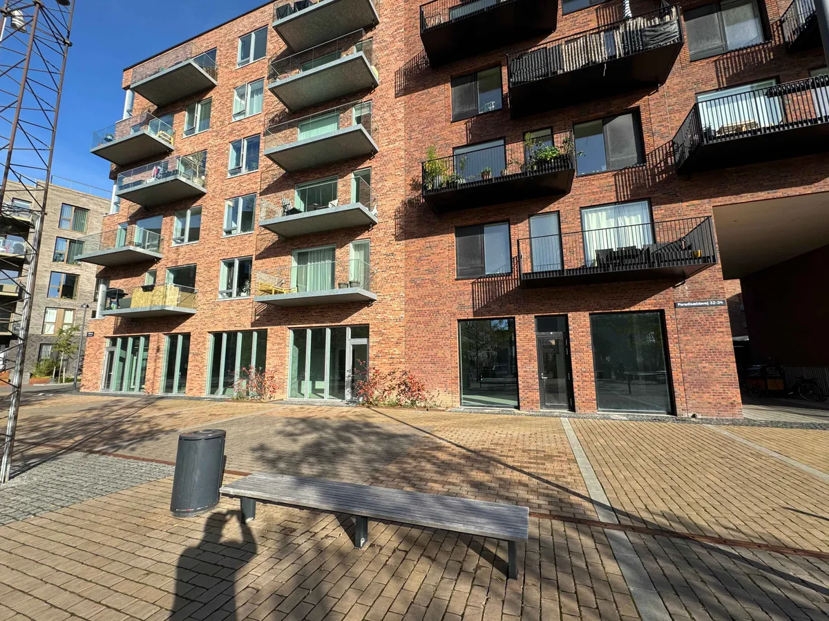 En stor rødmaurstensbygning med balkoner og terrasser samt en udsigt til Paradisæblevej 36.