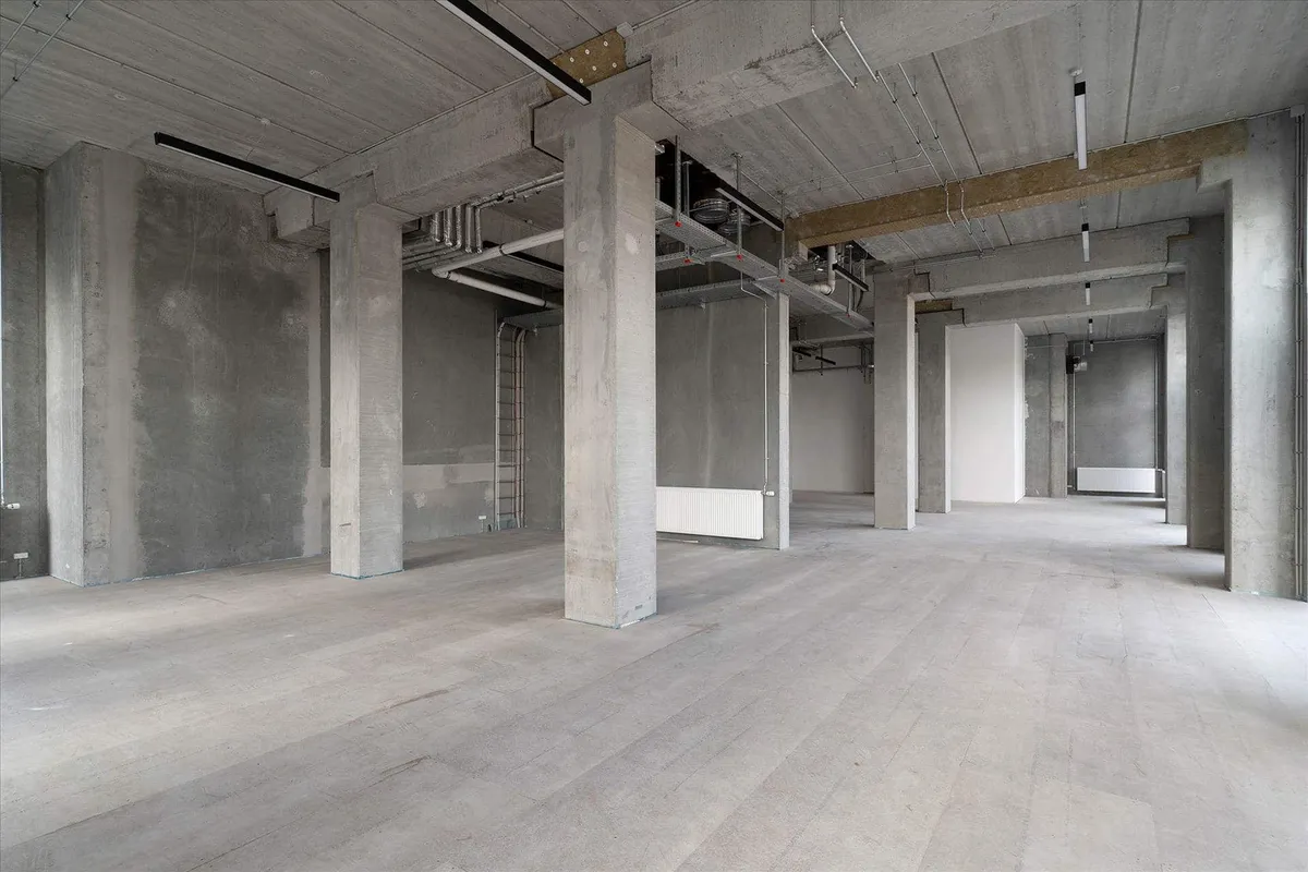 Moderne, industriel industrihal med betongulv, store søjler og åbne lofter med kabelkanaler og ventiler i loftet