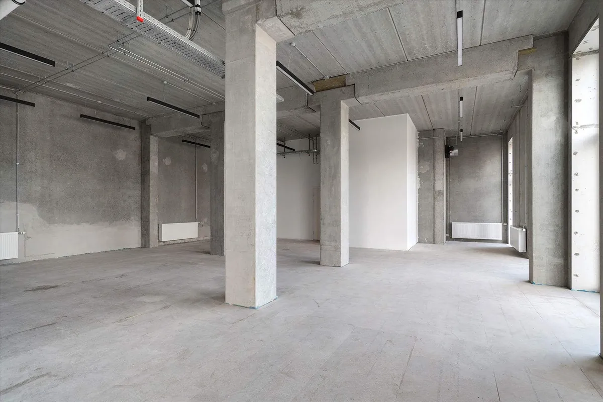 Store erhvervslokaler med højt til loftet og eksponeret beton samt hvide vægge og gulv og store vinduer