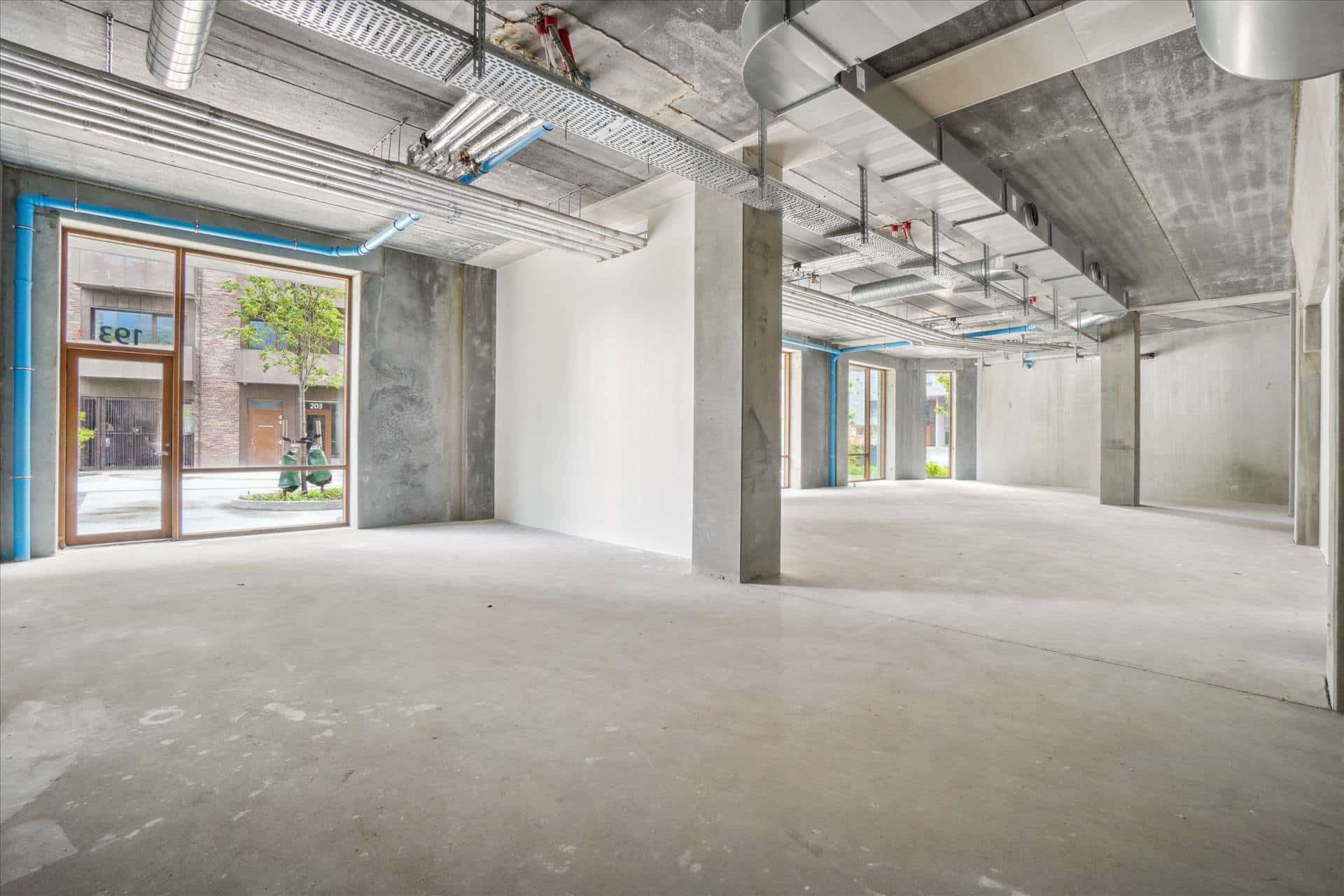 Store vinduespartier og højloftet lejemål i kvarteret med udsigt til grønne træer og bygninger på Njalsgade