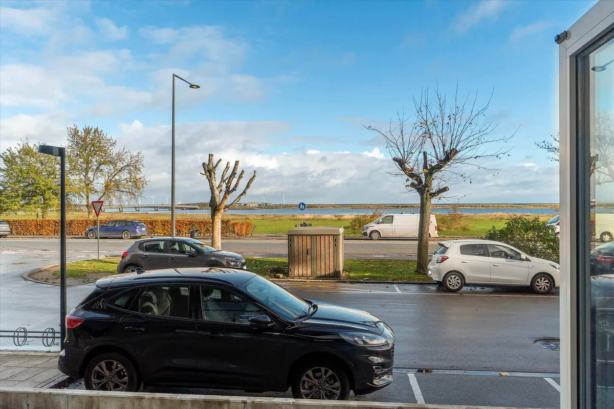 Sort SUV parkeret i en parkeringsplads med udsigt til havnen og søen i baggrunden. Strømpeholdere og tomme busser parkeret