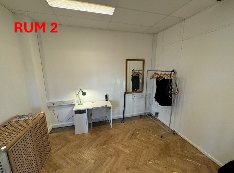 En kontorvirksomhed med rum nummer to, som har en hvid skrivebord, en grøn lampeskærm, en spejl og en klædeskab