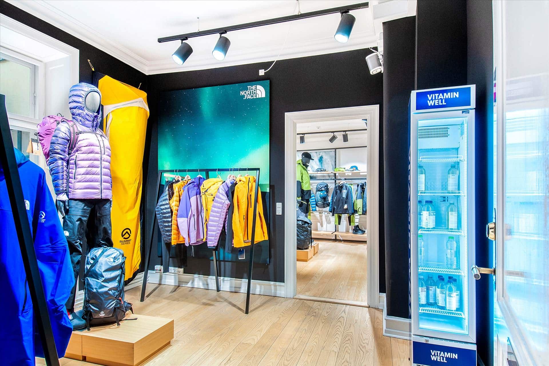En The North Face-butik med mærkeskilt, varer og en vitaminvendingsmaskine i et moderne og minimalistisk interiør med hvide