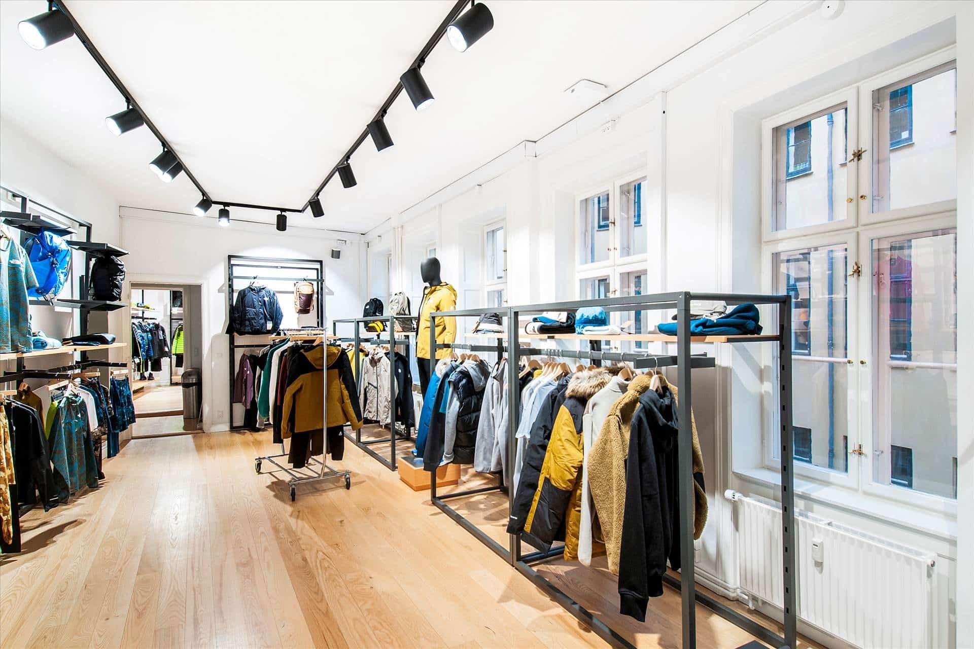 Et stort og rensliset boutique med klædeskab og varer udsat på stativer og vægge