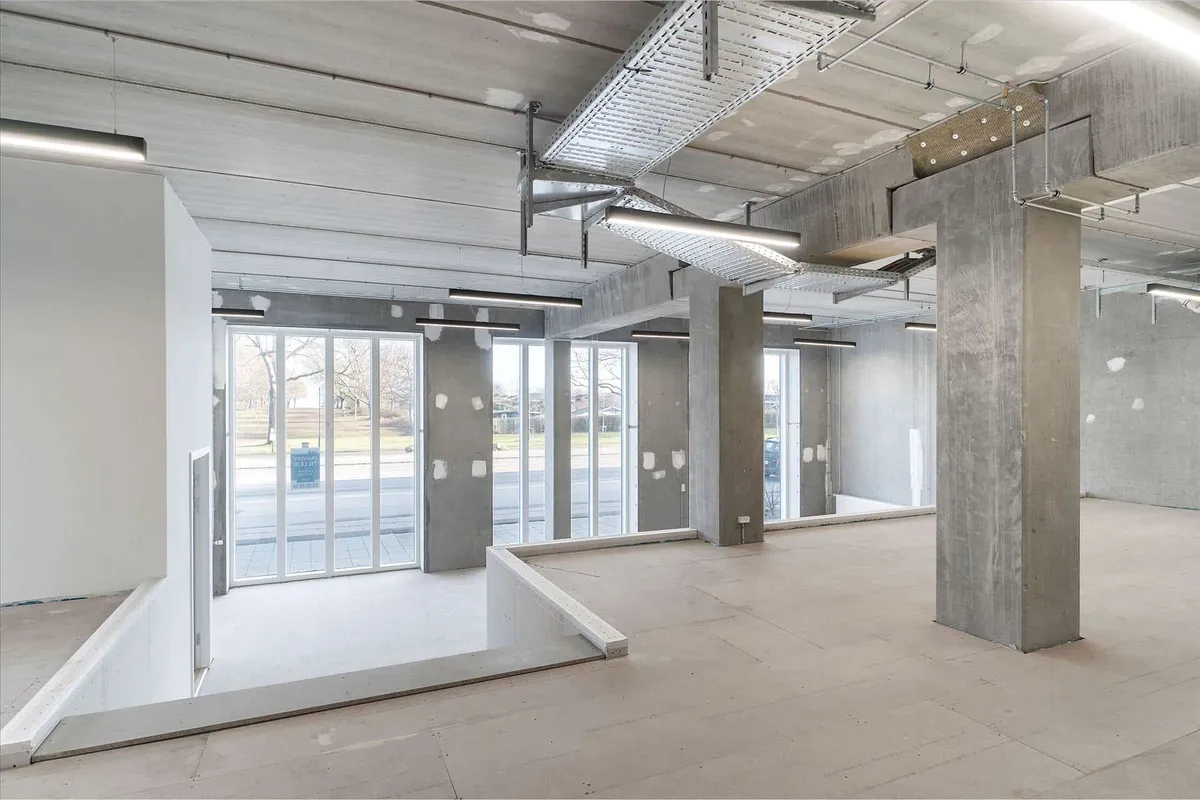Store glasruder, lyse lofter og rene gulve i et moderne erhvervslokal med beton søjler og åbne vindueskarme