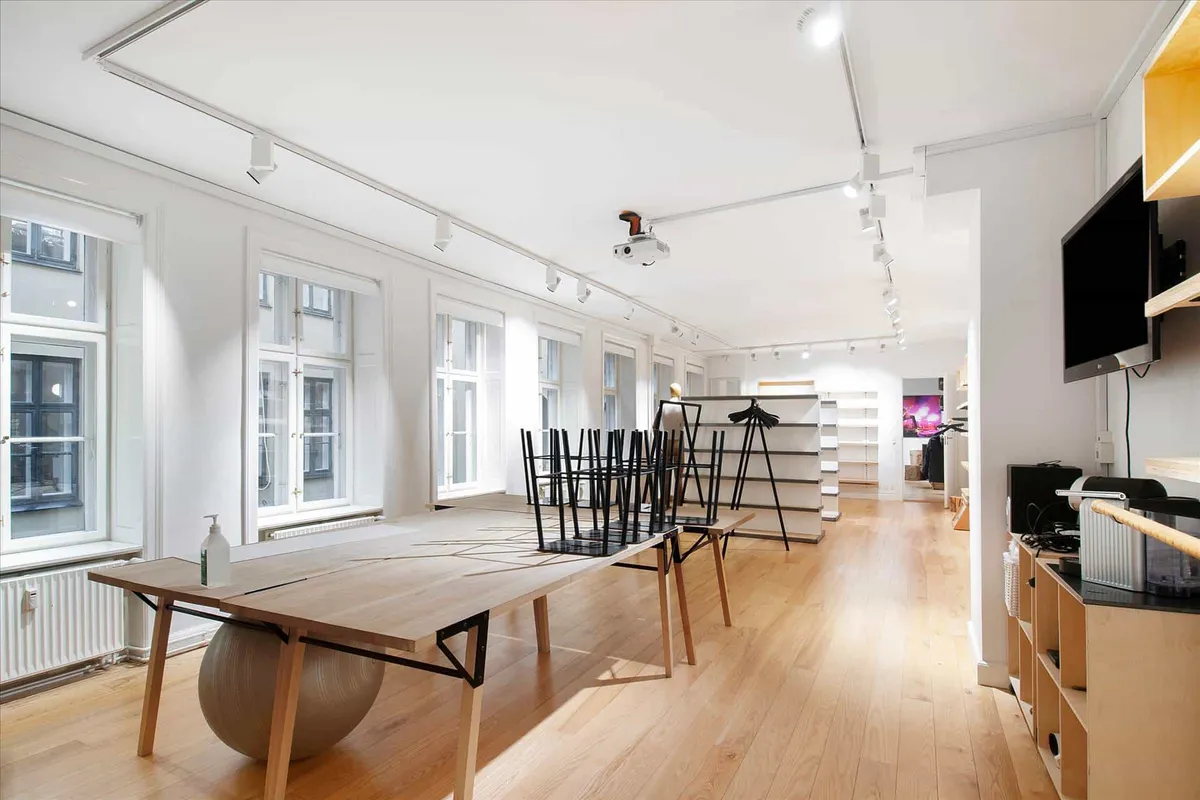 Minimalistisk interiør med lyse møbler og glasvinduer, der ud til gaden, sammen med teknologi og kunstværker