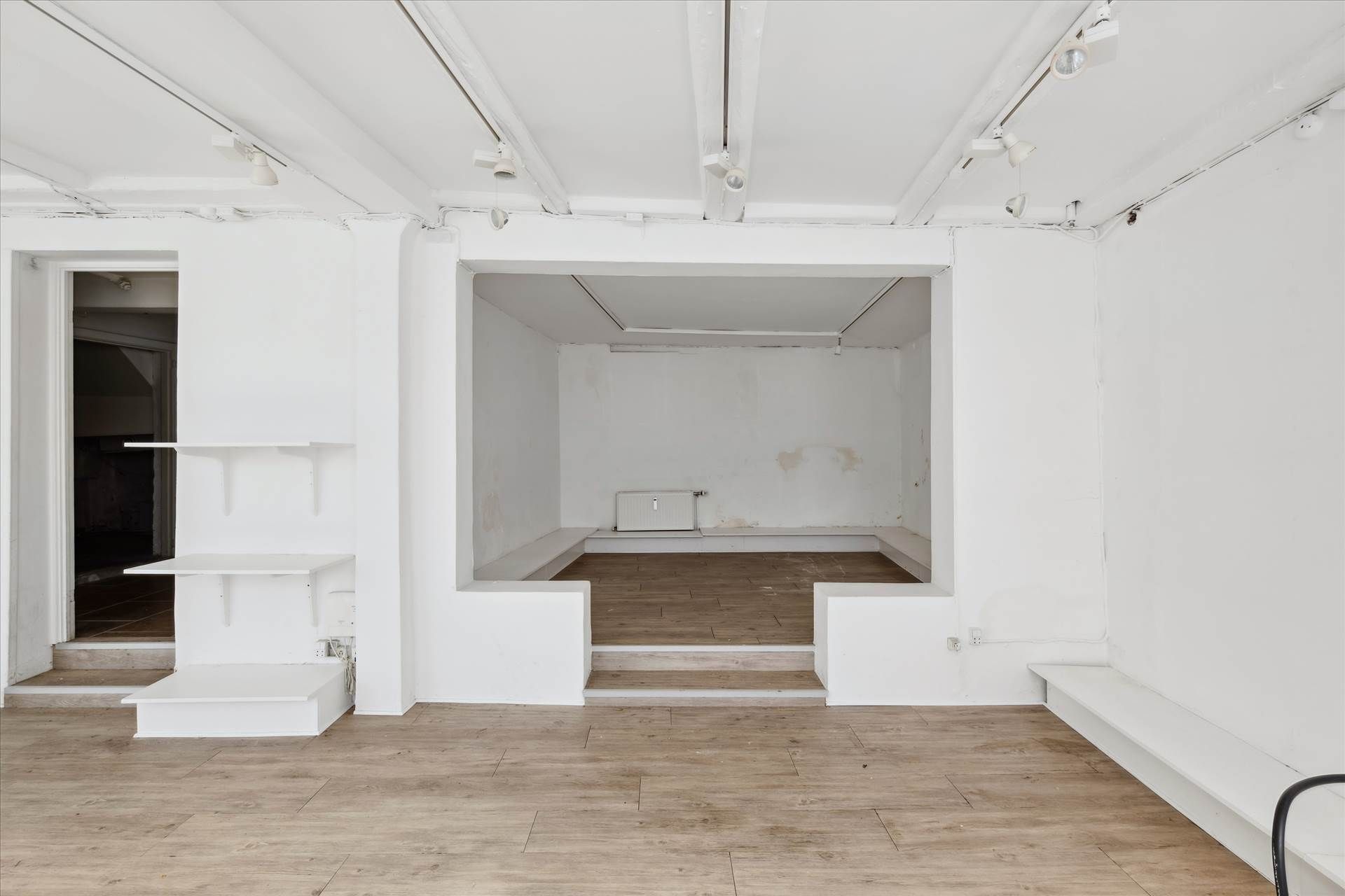 Store butikslokale med lyse, lyseblå lofter og hvide vægge samt lyse trægulve, moderne oplysning og møbler