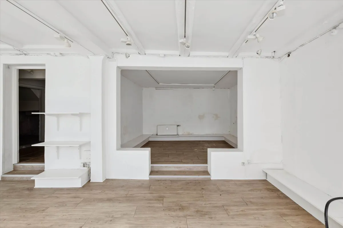 Store butikslokale med lyse, lyseblå lofter og hvide vægge samt lyse trægulve, moderne oplysning og møbler