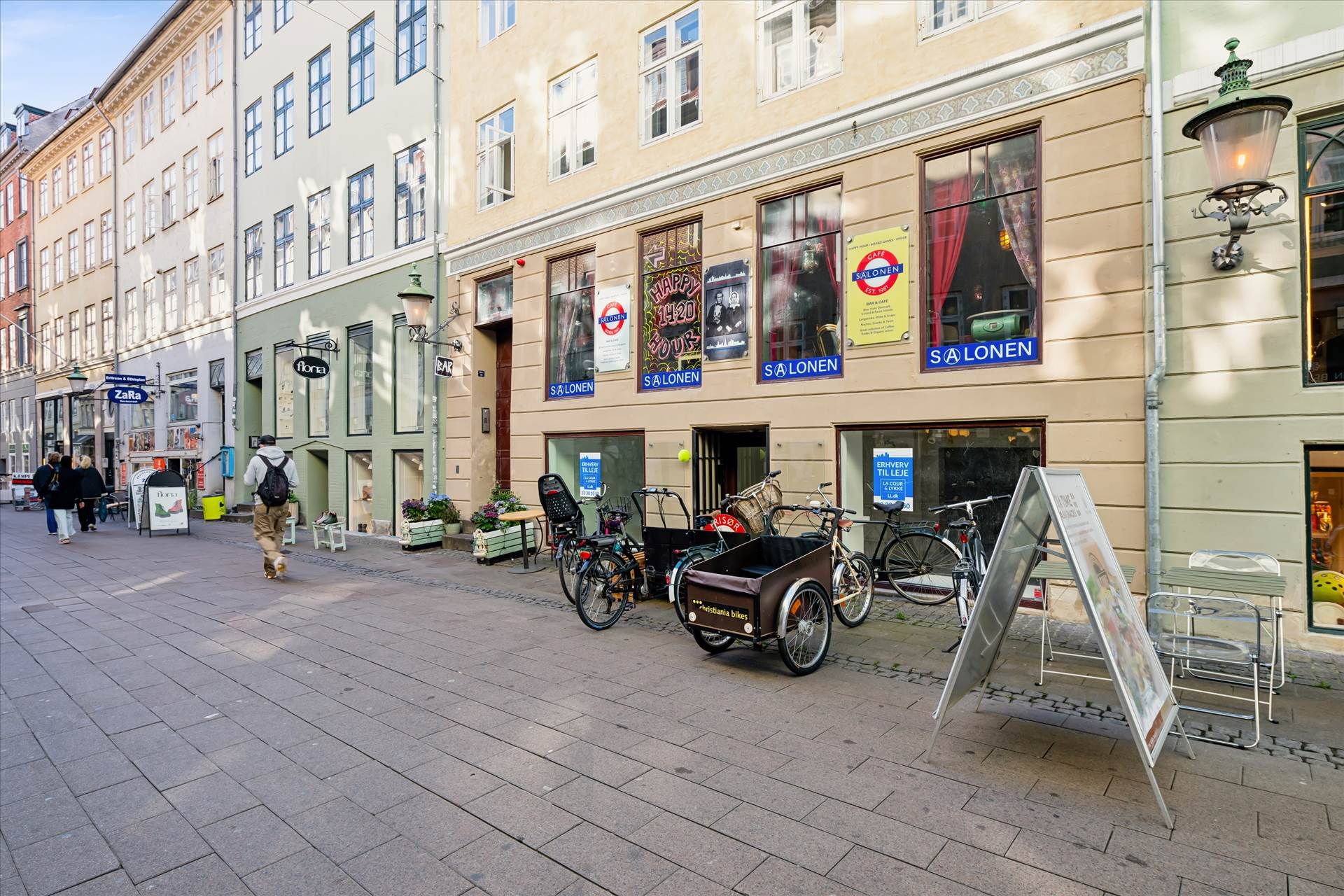 Butik med flere cykler og en trævogn parkeret foran. Kælenavn er Salonen. Butikken er i Fiolstræde, 100 meter fra Nørreport