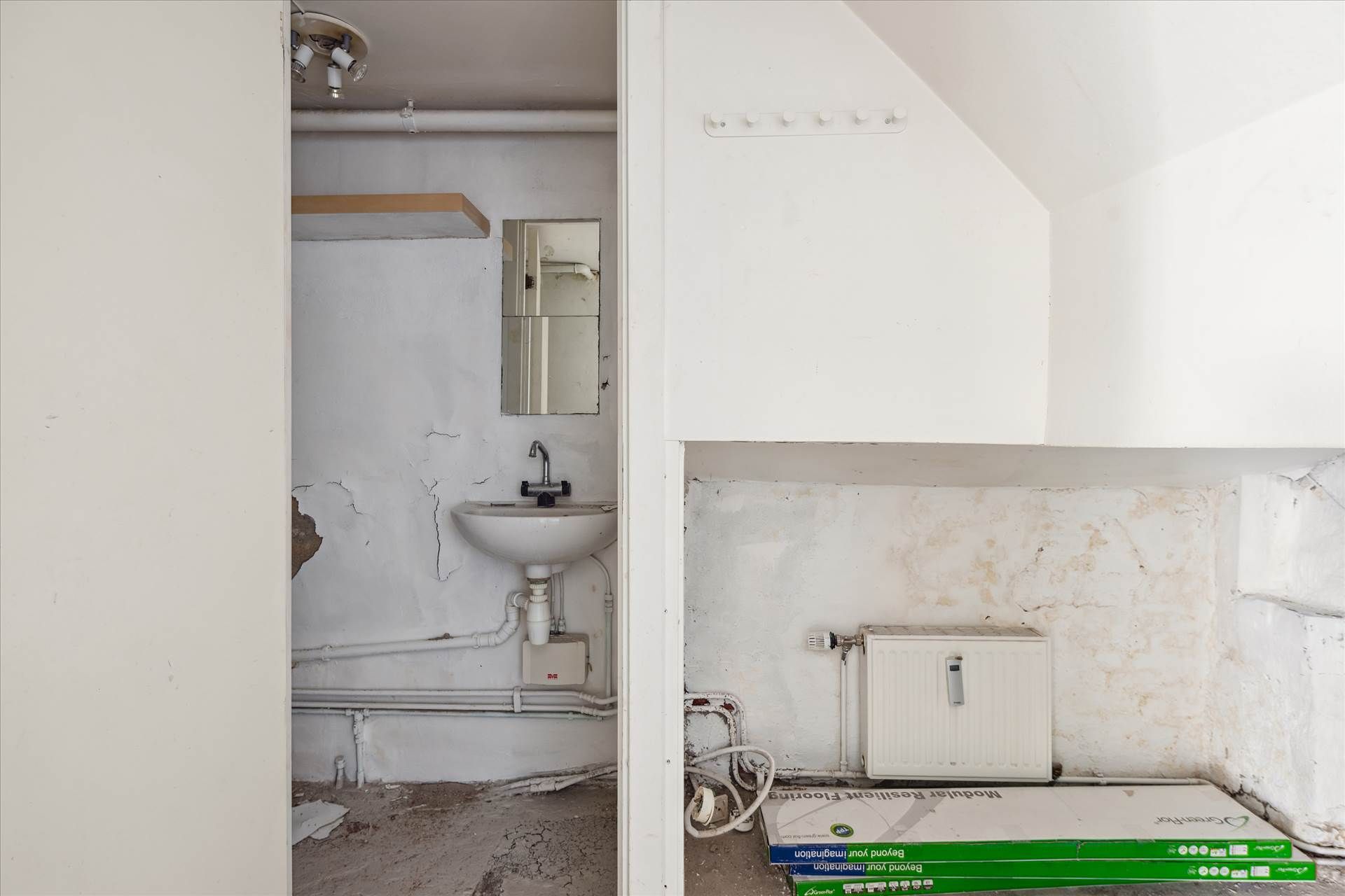 Værelse med lysekron, spejl, hvidt toilet og badekar, samt søjle med radiator og støjskalle