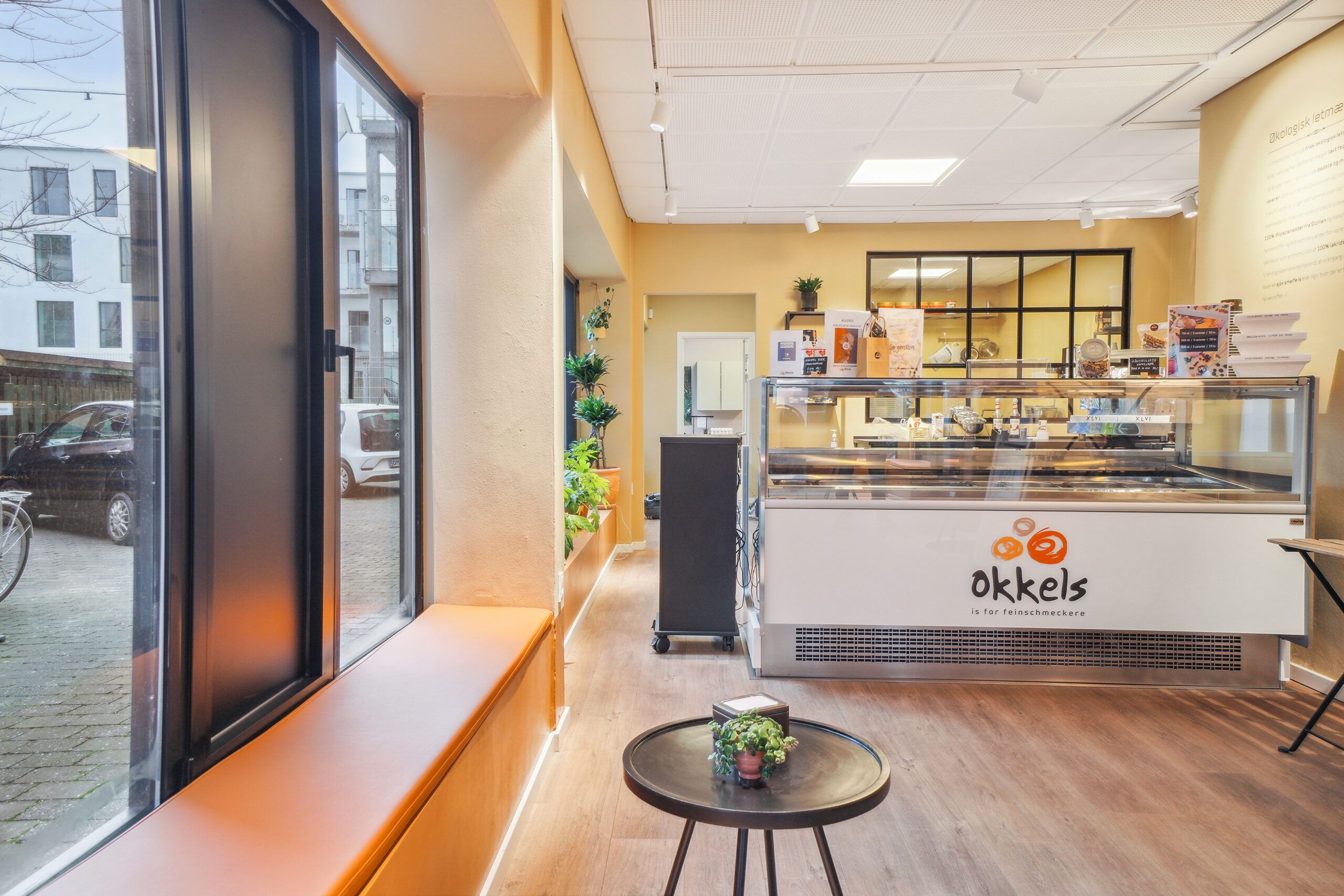 Inde i en dejlig kafe med gule vægge og en stol med et plantepotte. Der er en lille rund bord med et plantepotte på.