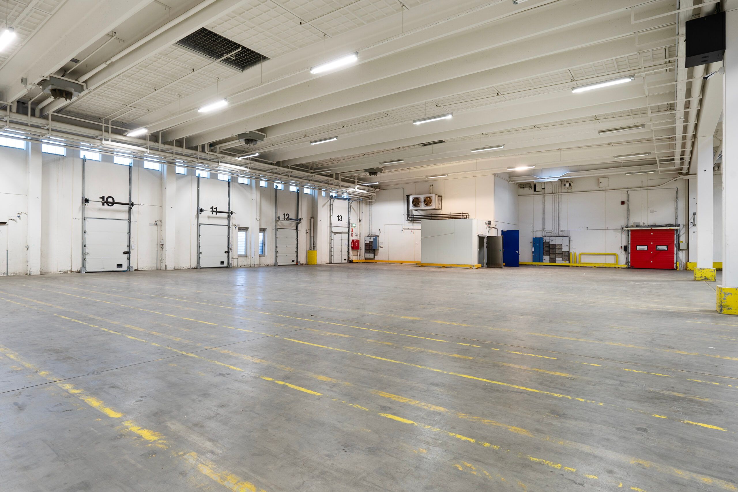 Lager med to store porte og flere mindre porte. Gulvet er mærket med gule linjer og nummererede døre