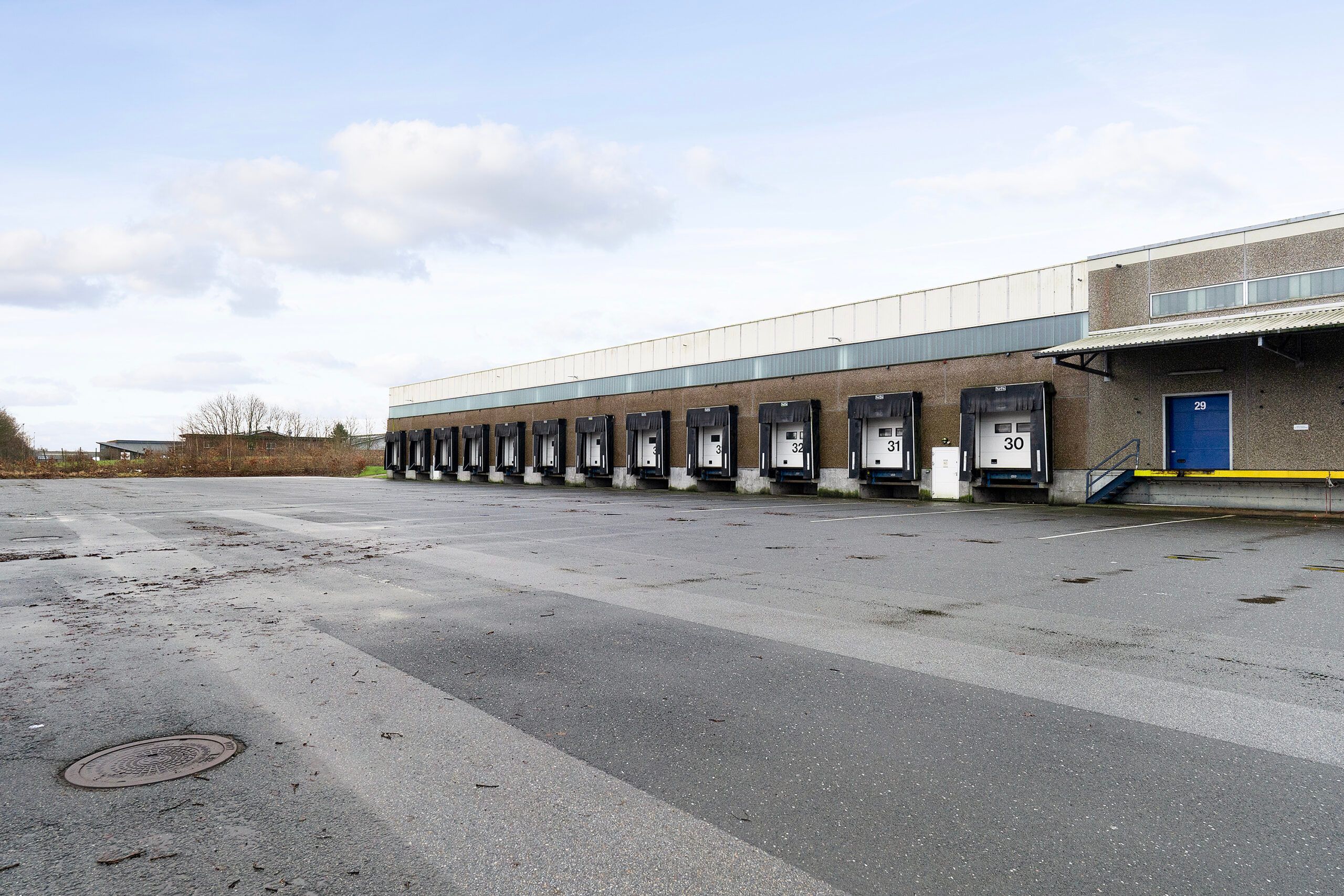 Regnfulde himmel med skyer og en stor lagerbygning med mange store hvide ladeport i Kolding