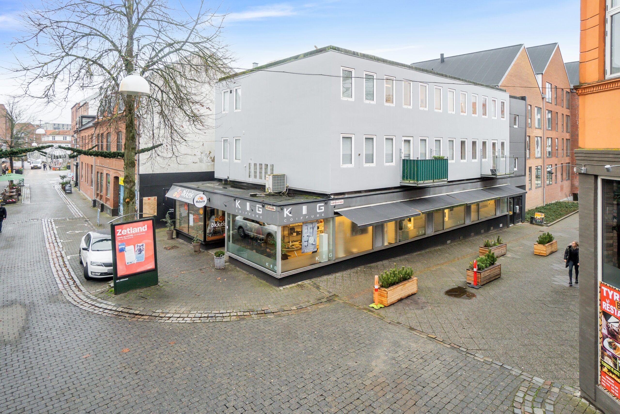 Moderne butik med stort glasvindue og Kig Kig skilt på hjørnet af en gågade i Kolding