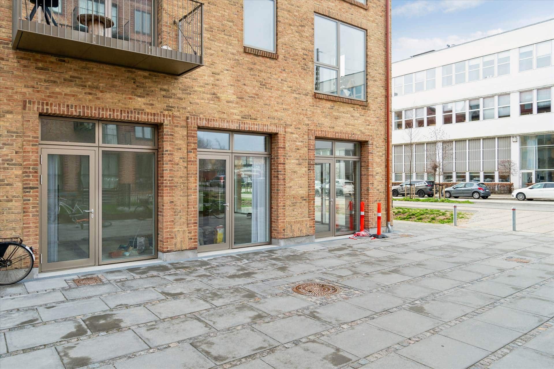 Store glasdøre med glaskurve og stige til første sal i nyopført hus med røde mursten og hjørnebeliggenhed