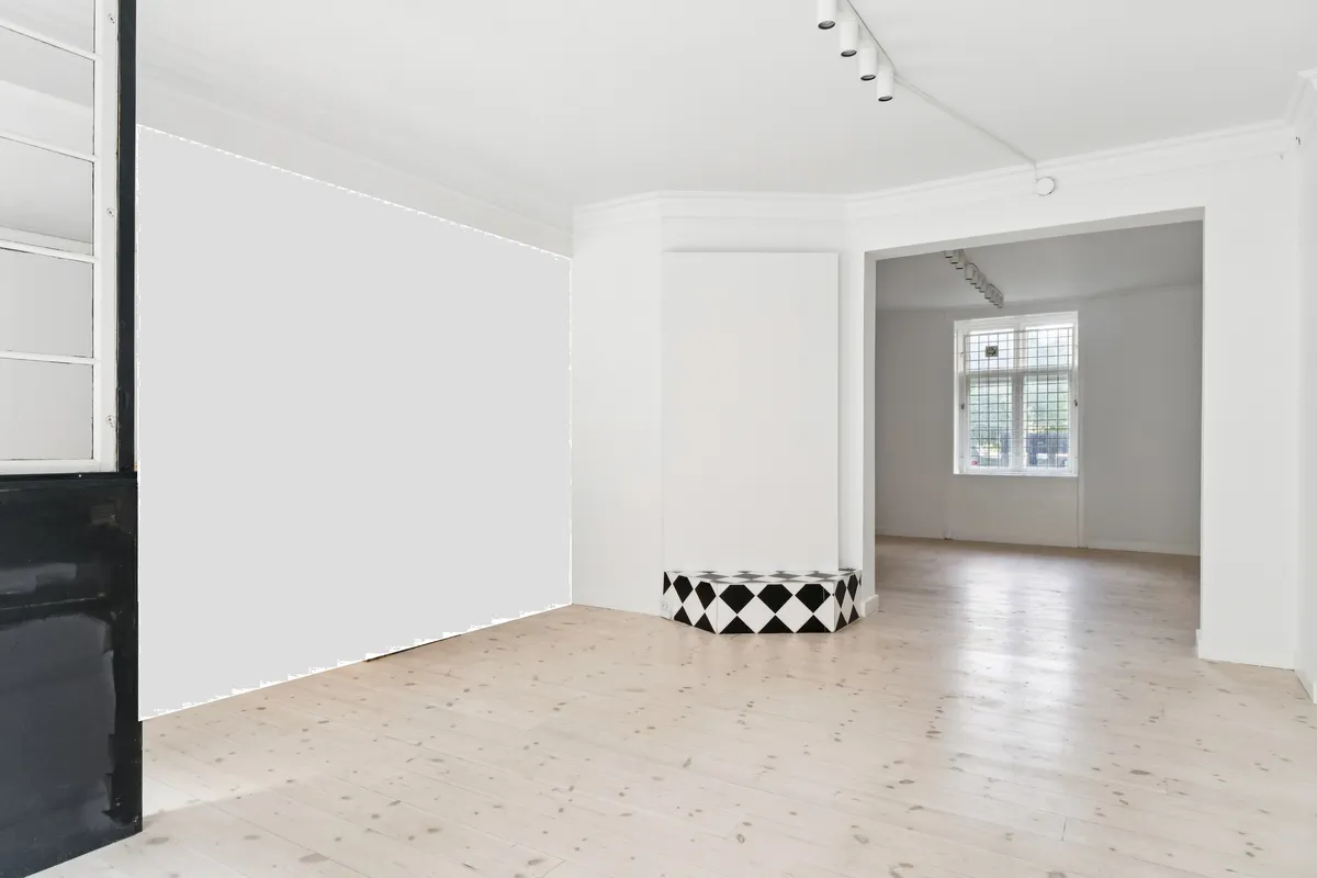 Moderne og minimalistisk butik med to rum og sort hvid krydsmønsteret stol i midten. Hvid gulvbelægning og hvide vægge med hvide møbler og lys.