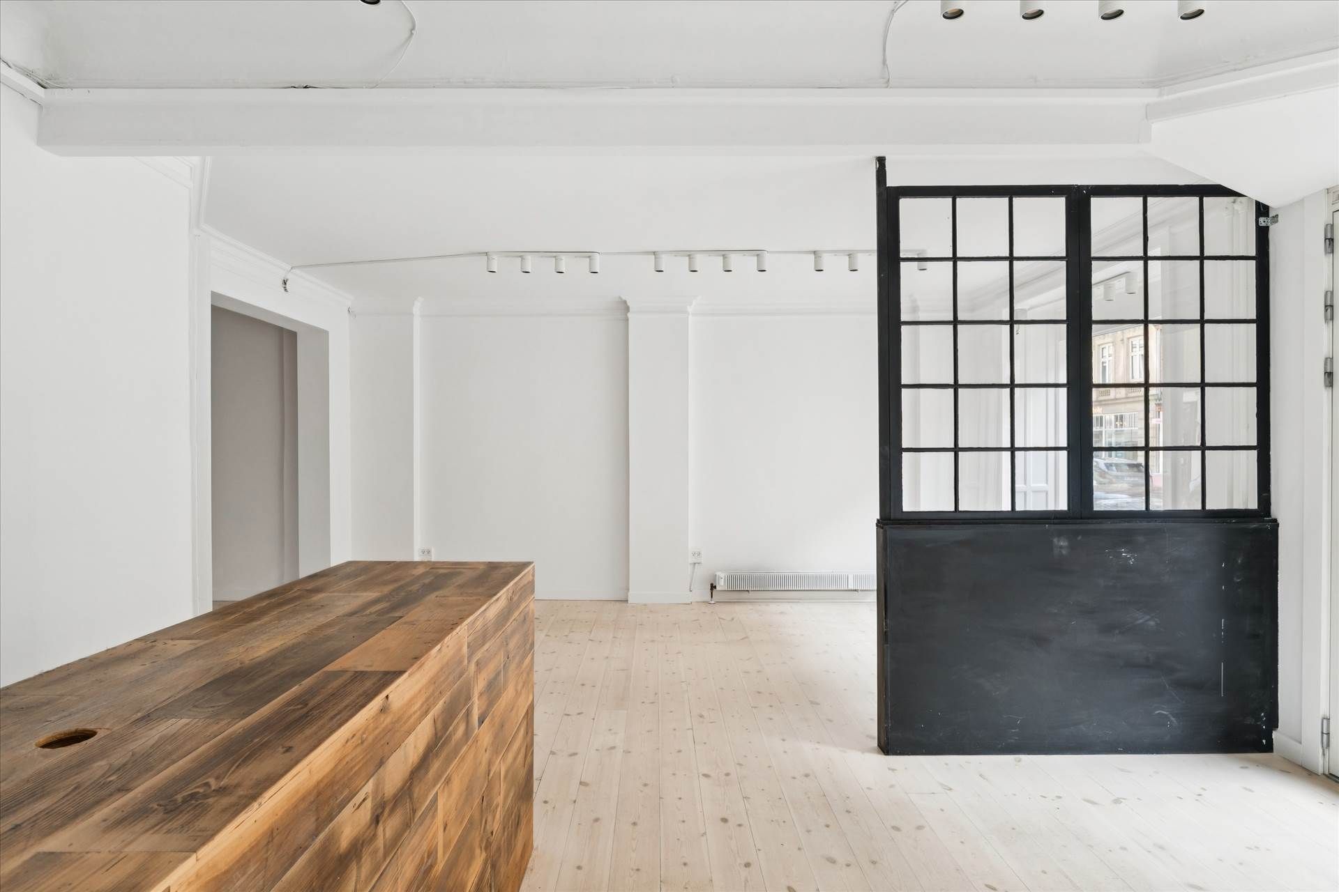 Et stort værksted med højt loft og åben dør til gården med lyse og vinduer