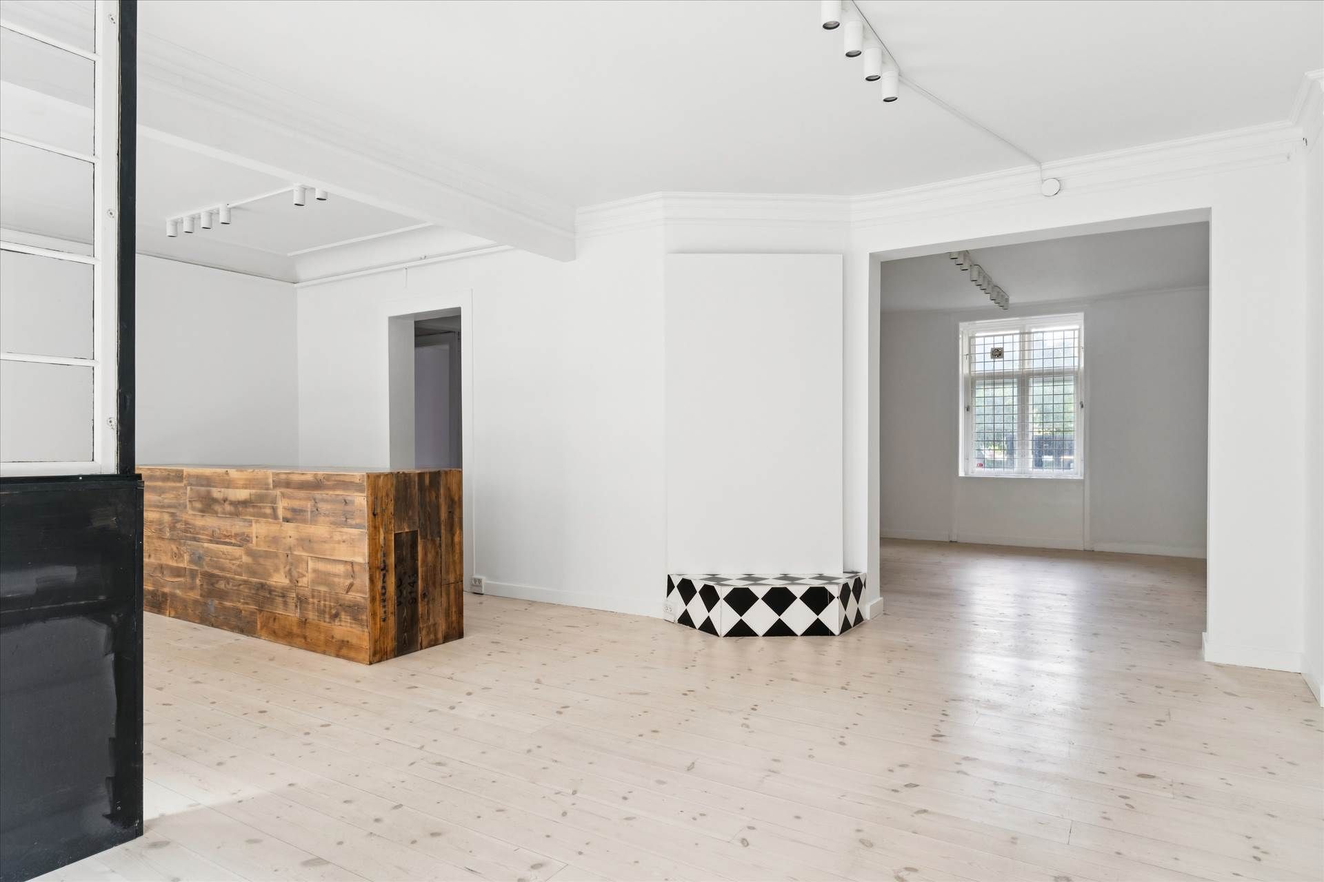 En ubenyttet kontorlokale med lyse vægge og loft samt et træbord og en stol med mønstret