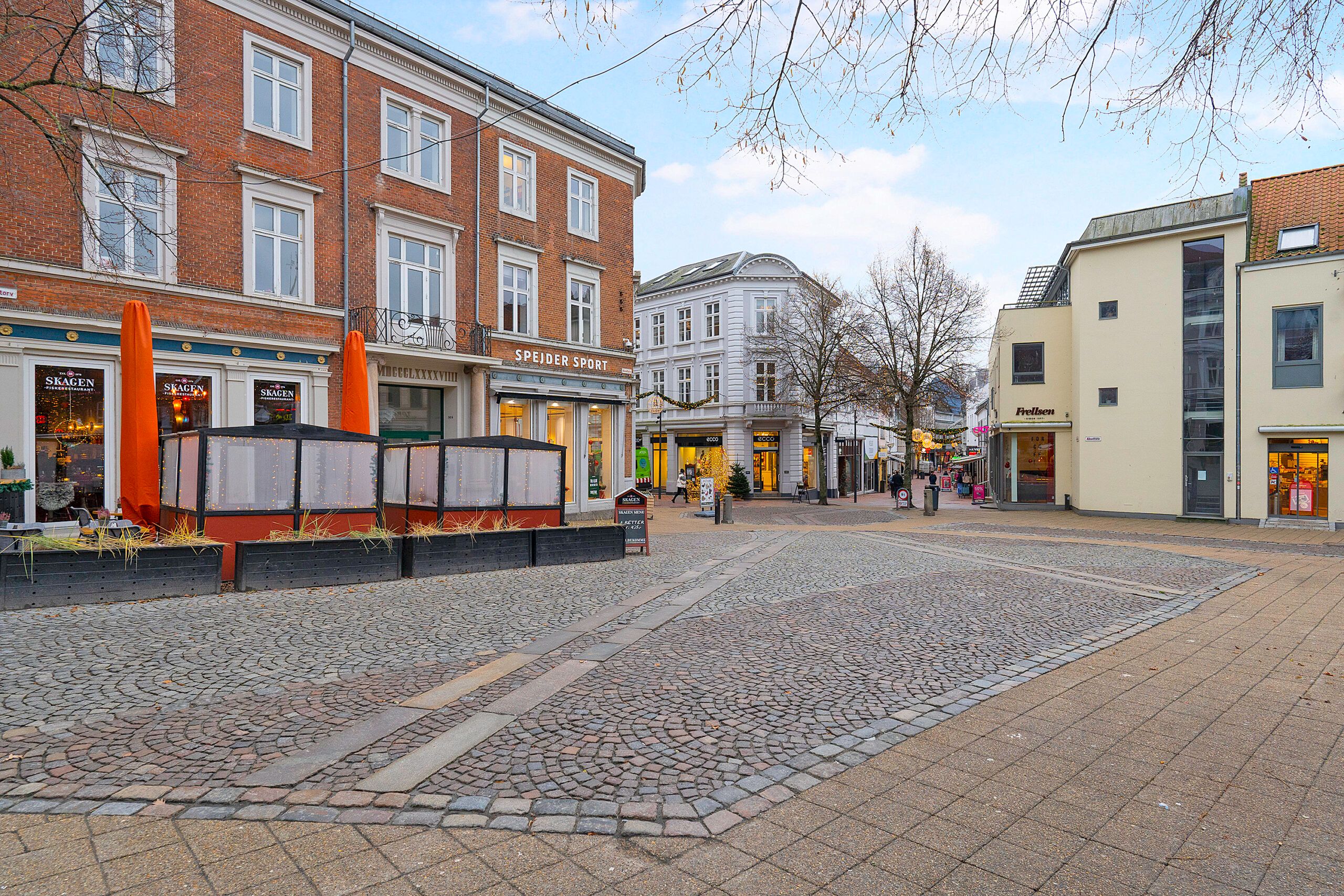 Lejlighedsbygning med forretninger og caféer i bymidten af Kolding med skovej og pavilloner