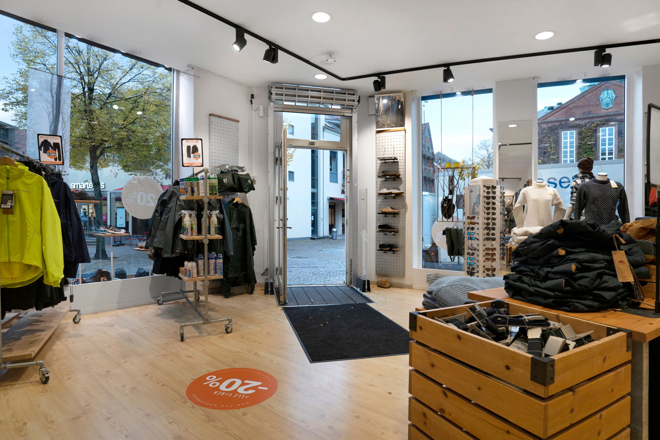 Inde i en butik med solbriller, tøj og sko, hvor der er en stor udsalgsskilt med rabat på 50%.