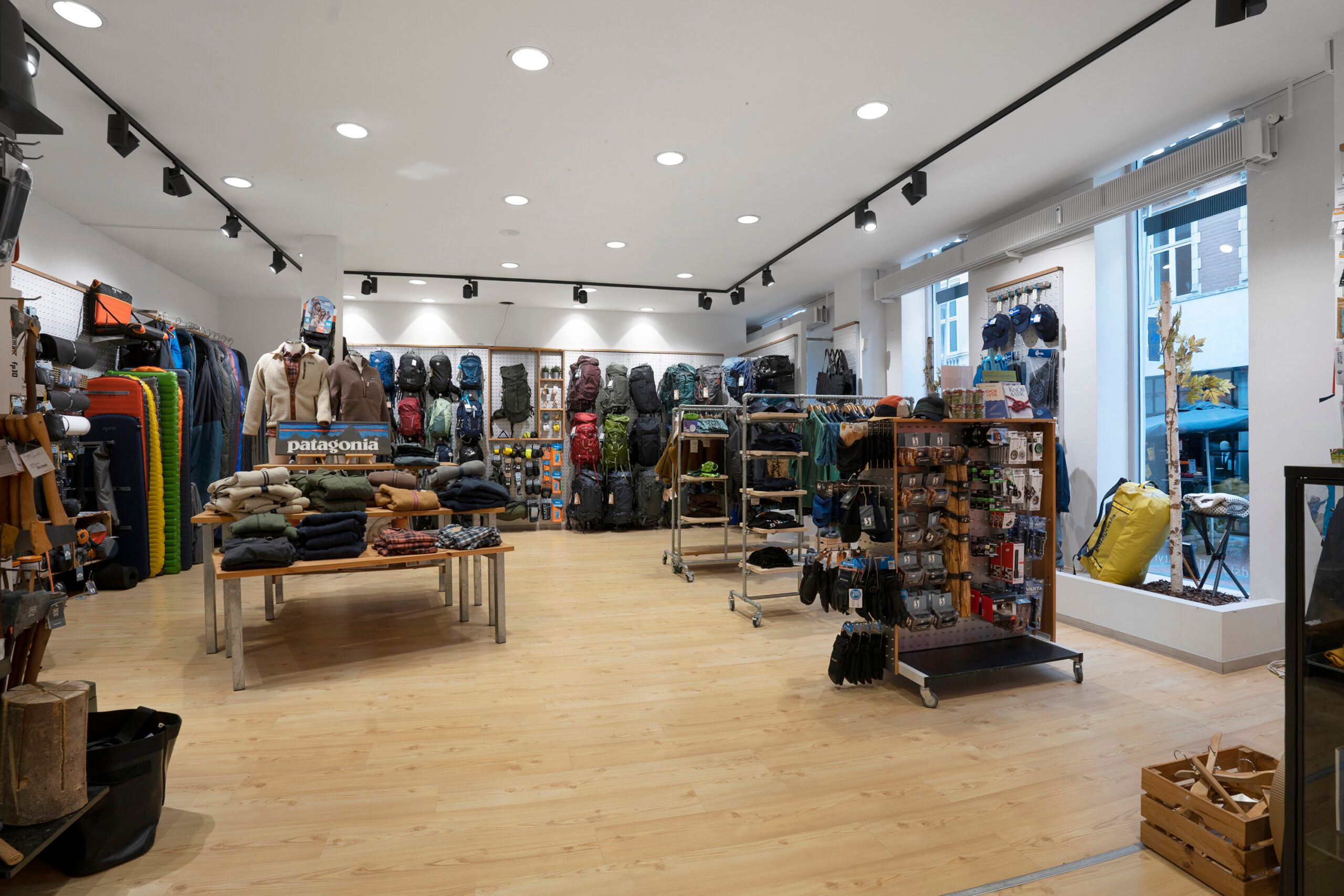Lejligheden indeholder en stor butik med udstyr til udendørs, herunder rygsække, tøj og campingudstyr, med trægulve og