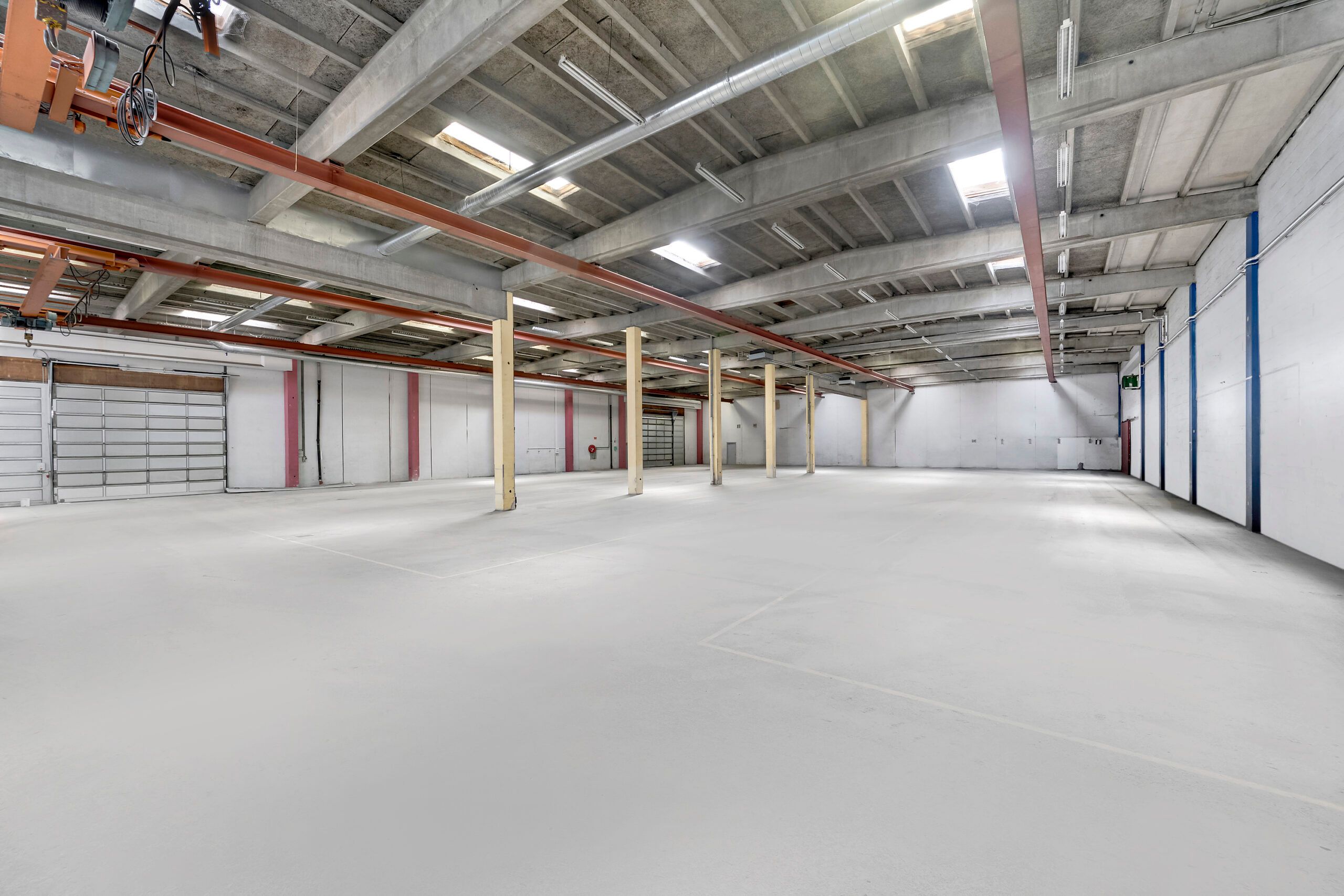 Lager med 830 m² og 6 meters loftshøjde, oplagsmuligheder udenfor og garagedøre i hvidt og rød accent