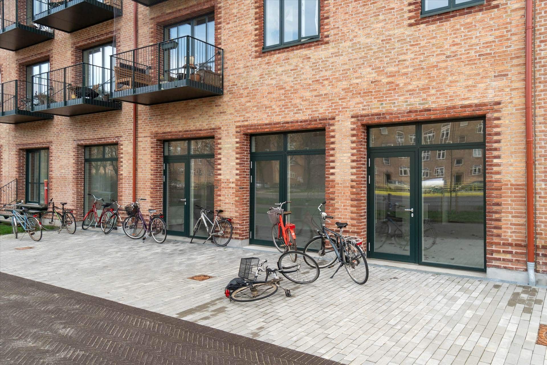 Mange cykler er parkeret foran nye boligher, og en af dem ligger sammenbrudt på jorden