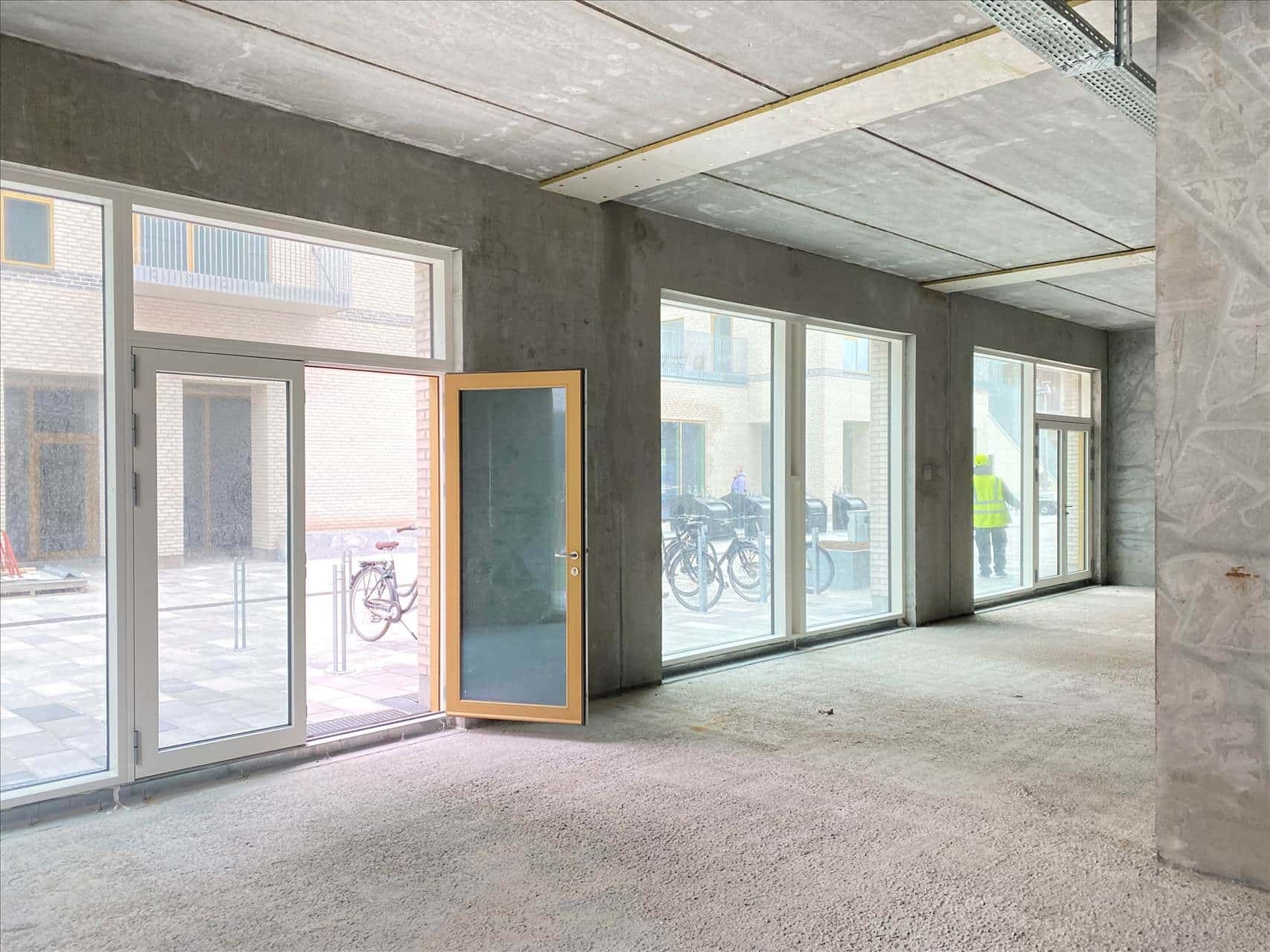 En tom forretningslokal i Rødovre med store vinduer og gulvbelægning i gangen og udvendigt.