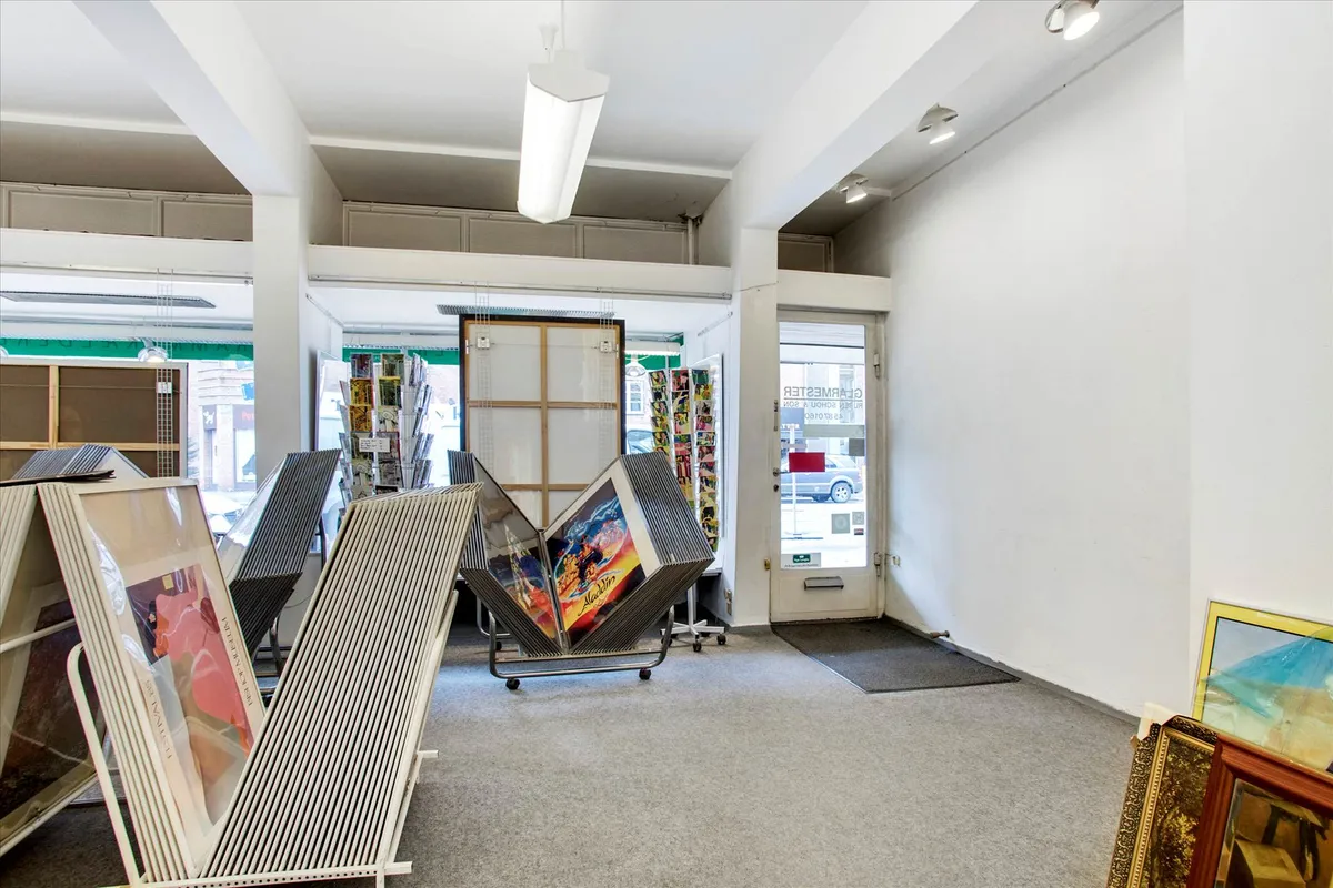 Store smykkeskabe i en butik med facadevinduer, et lysekron og kunstværker og malerier i hallen og på væggen