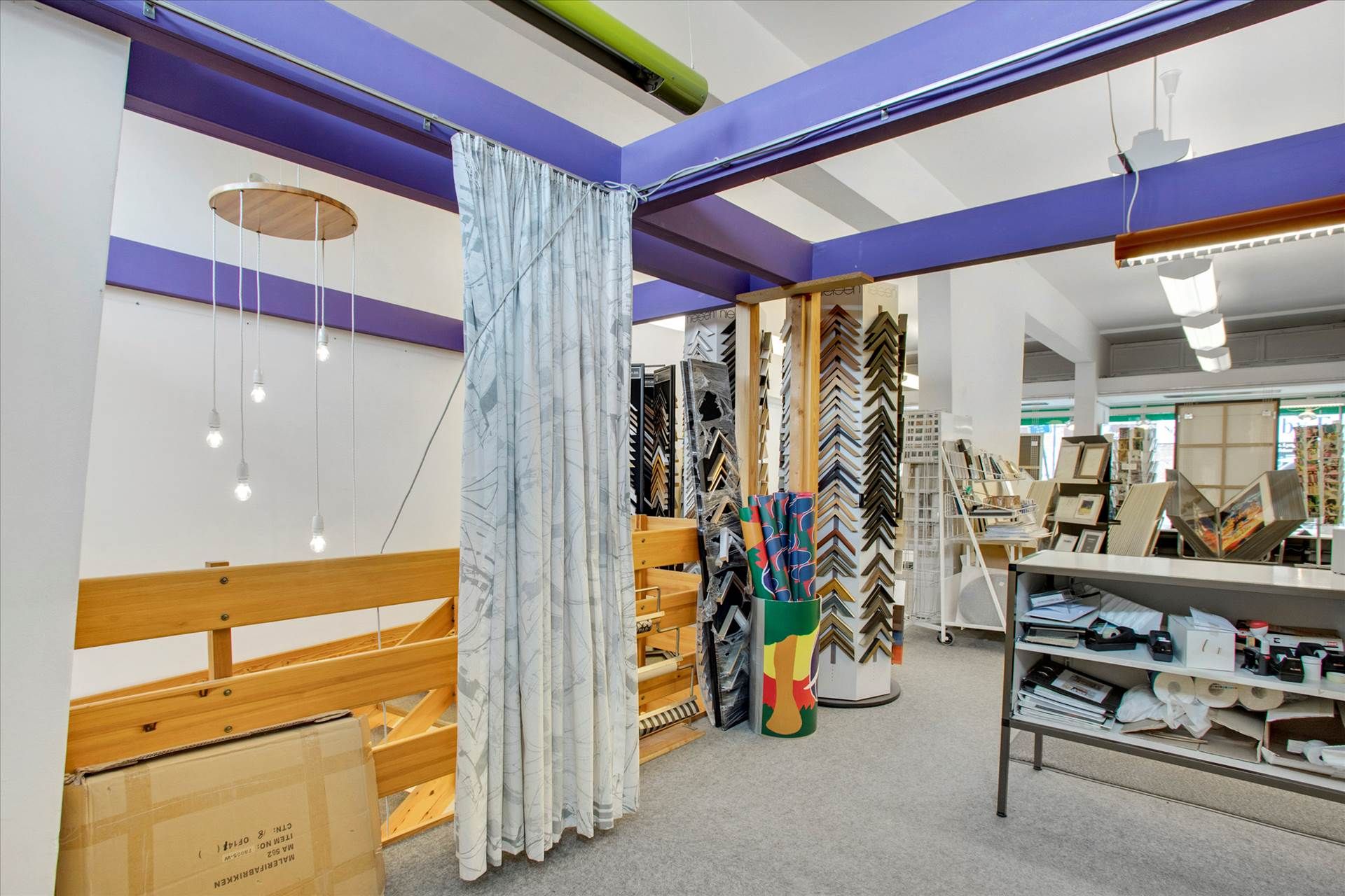 Moderne indretning i en butik med højloftede rum, lyskroner, lyse pærer og kurve med rullemateriale