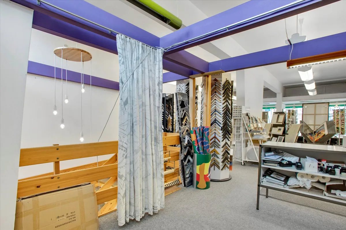 Moderne indretning i en butik med højloftede rum, lyskroner, lyse pærer og kurve med rullemateriale