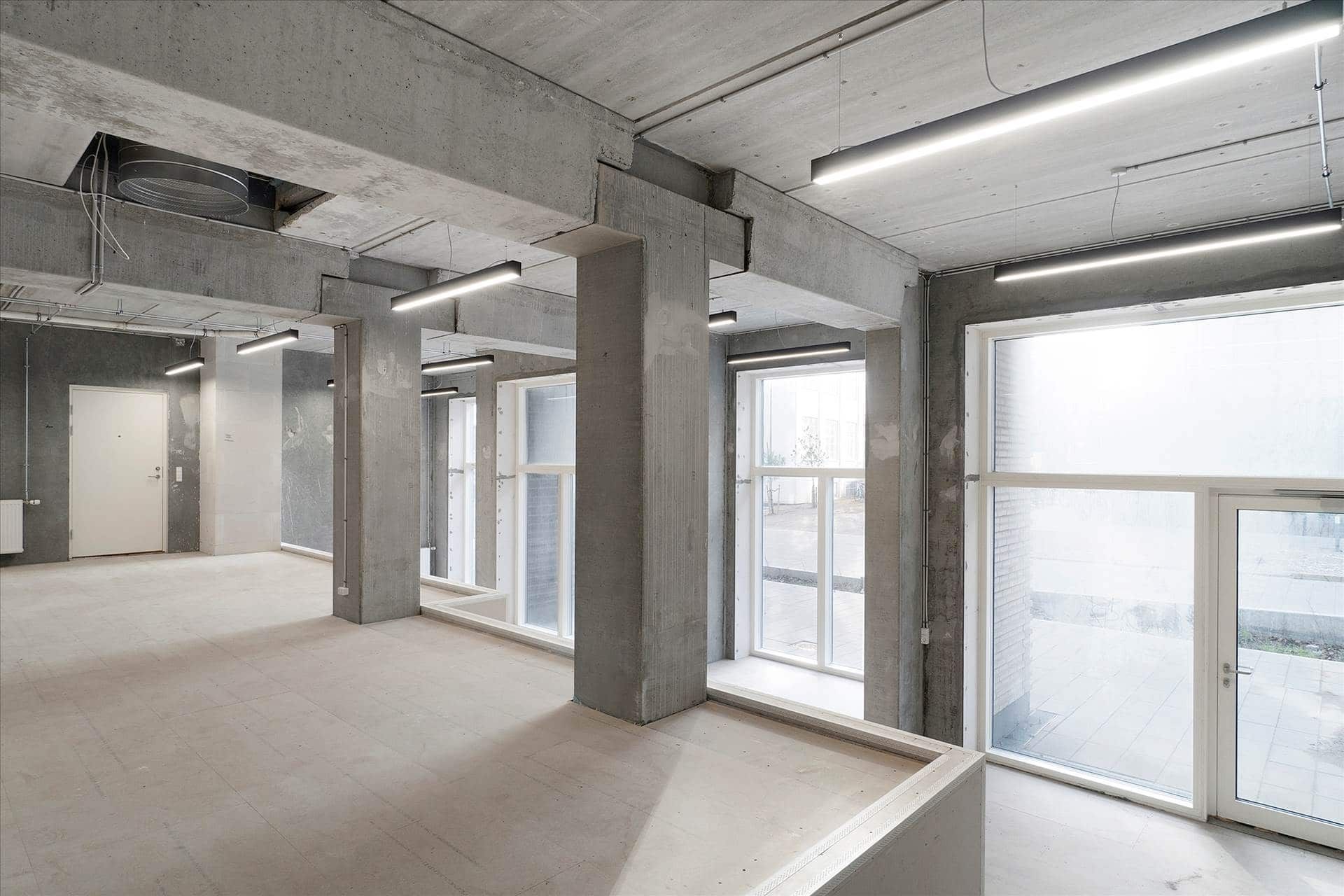 En stor, tom kontorfællesskab med højt til loftet og store vinduer og lysekroner