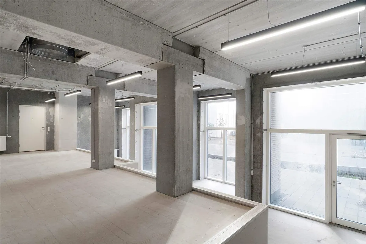 En stor, tom kontorfællesskab med højt til loftet og store vinduer og lysekroner