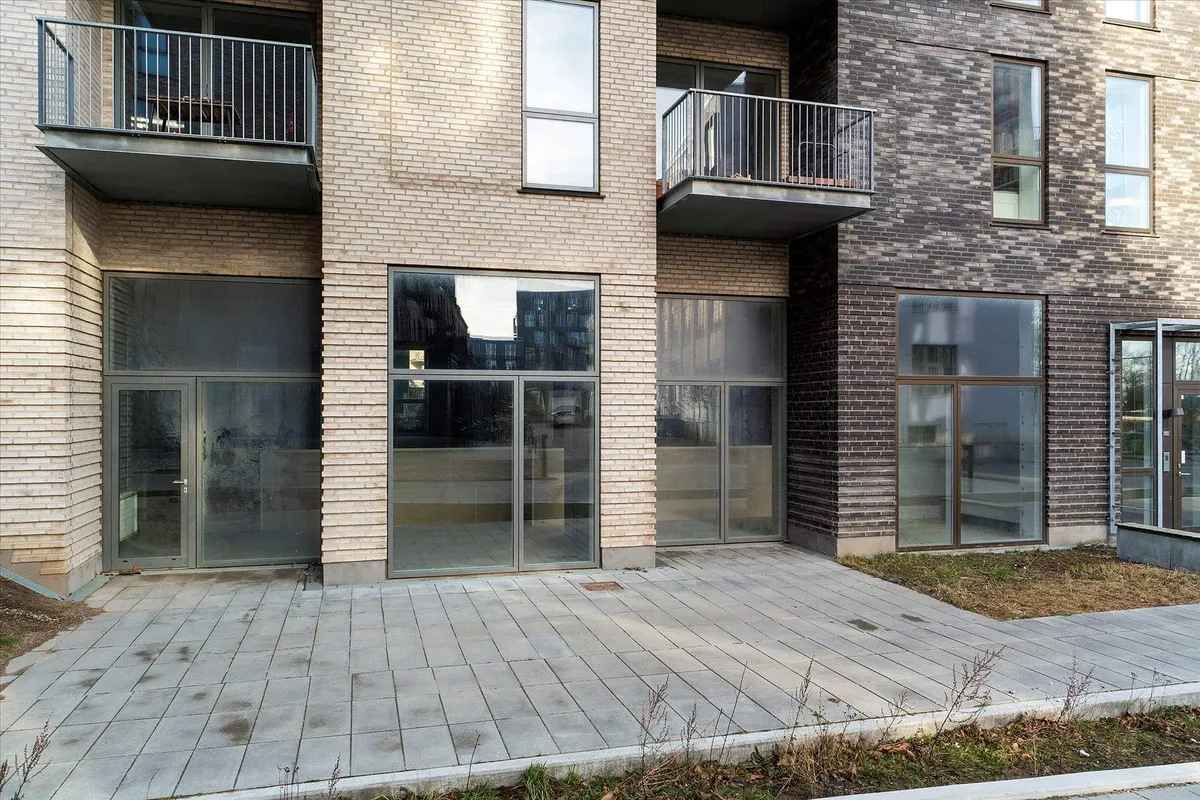 En ny bygning med glasvinduer og en terrasse, hvor der er udsigt til søen og skoven