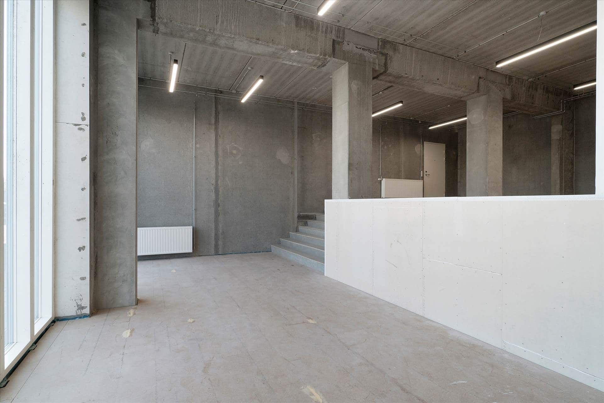 Et stort rum med højt til loftet, tørre vægge og hårdt gulv, åbne ruder og lyse loftslampe