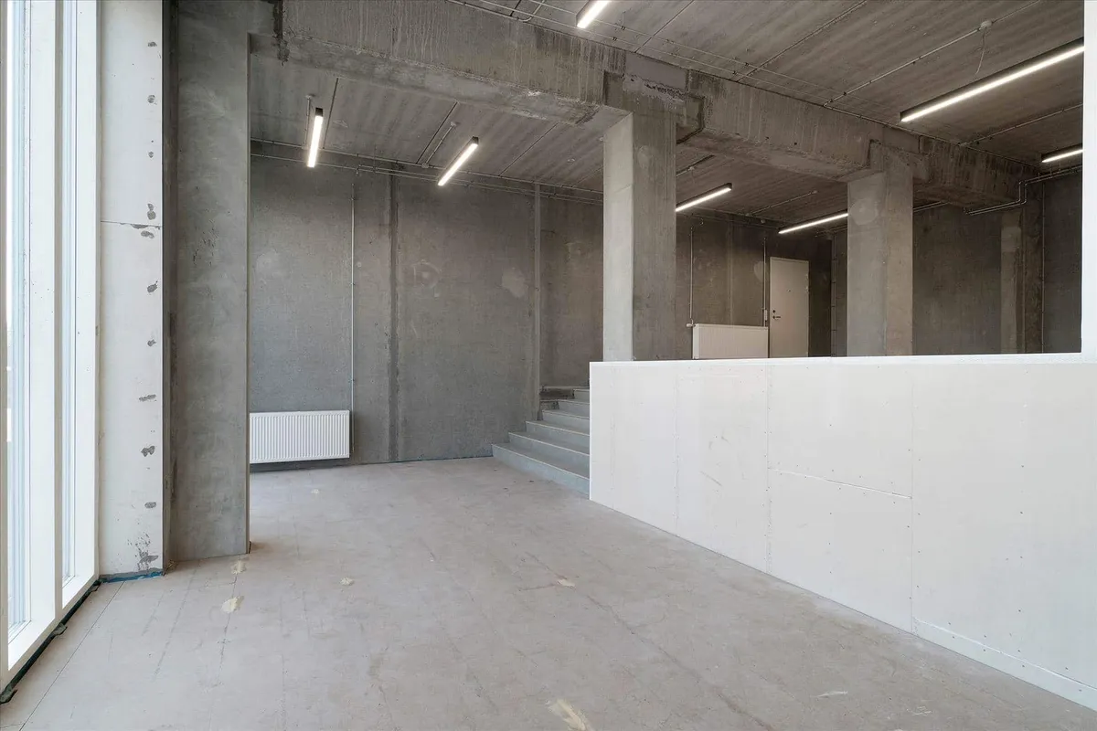 Et stort rum med højt til loftet, tørre vægge og hårdt gulv, åbne ruder og lyse loftslampe