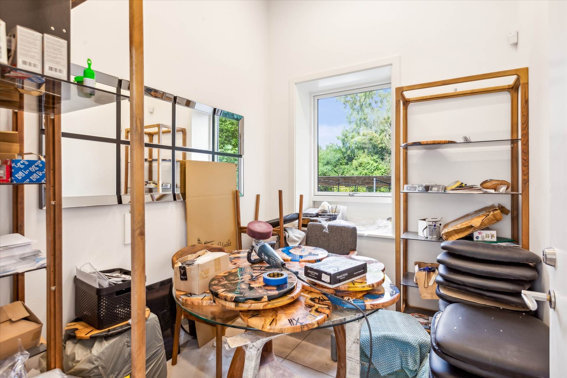 Tidligere lager med højt loft og vinduer, udstyret med hylder, borde, sæder, kasser og diverse objekter