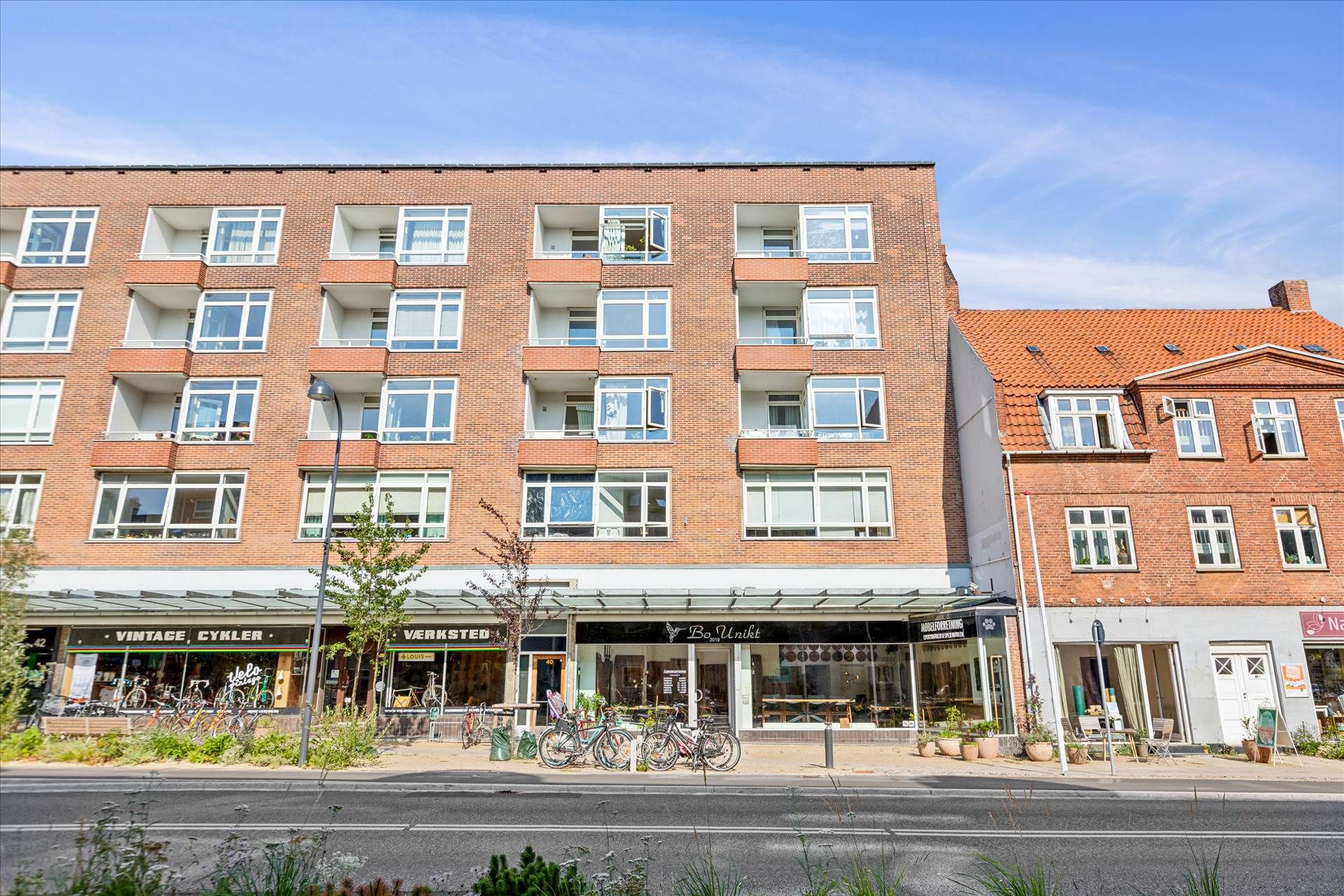 Store butikker med glasvinduer og udsigt til gaden. Et cykelreparationsfirma og et caféshowroom med udsigt til østlige