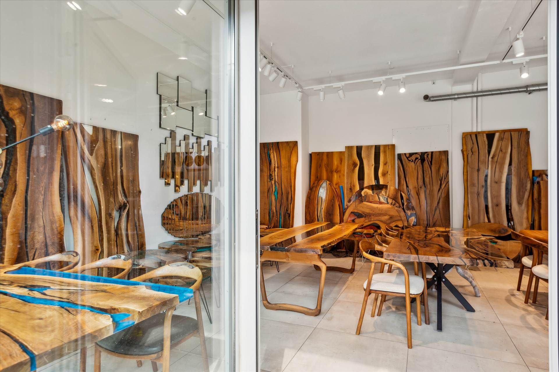 Showroom med flere træborde og stole samt vægmøbler og lysekroner i loftet